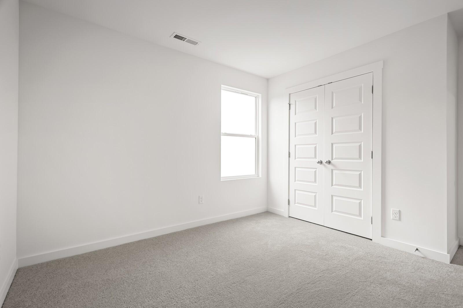 Bright bedroom with plush carpet and double-door closet in The Logan C floor plan at Calista Farms, White House, TN.