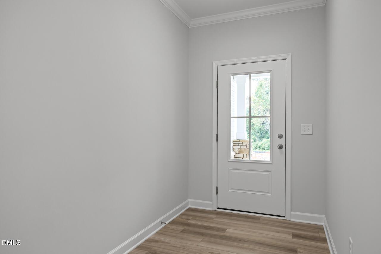 Bright flex room with light gray walls, glass-paneled exterior door, and wood-look floors in Davidson Homes The Hickory II B, Lillington, NC