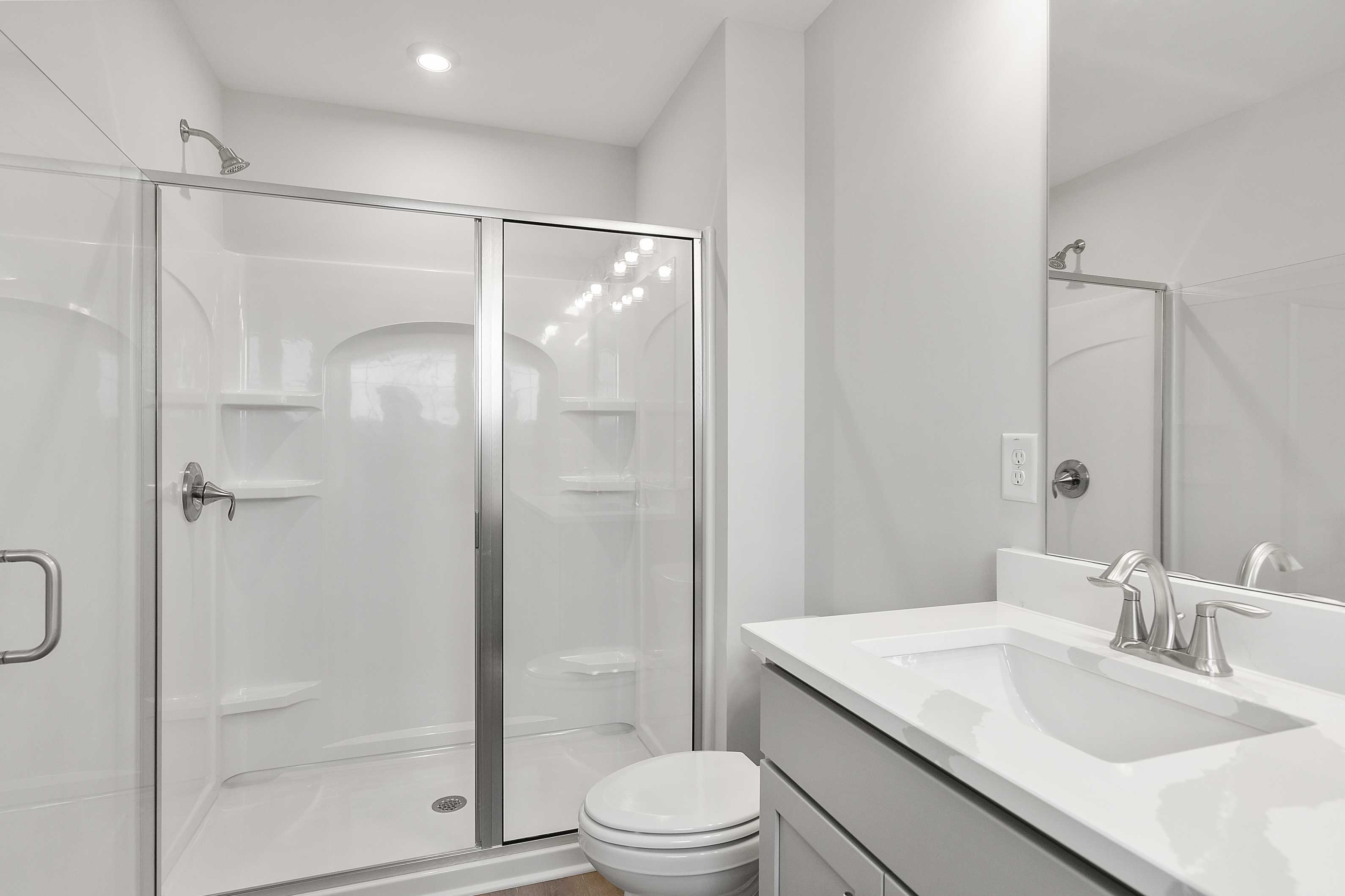 Elegant master bathroom in The Durant A with frameless glass shower, quartz vanity sink, and white tile accents