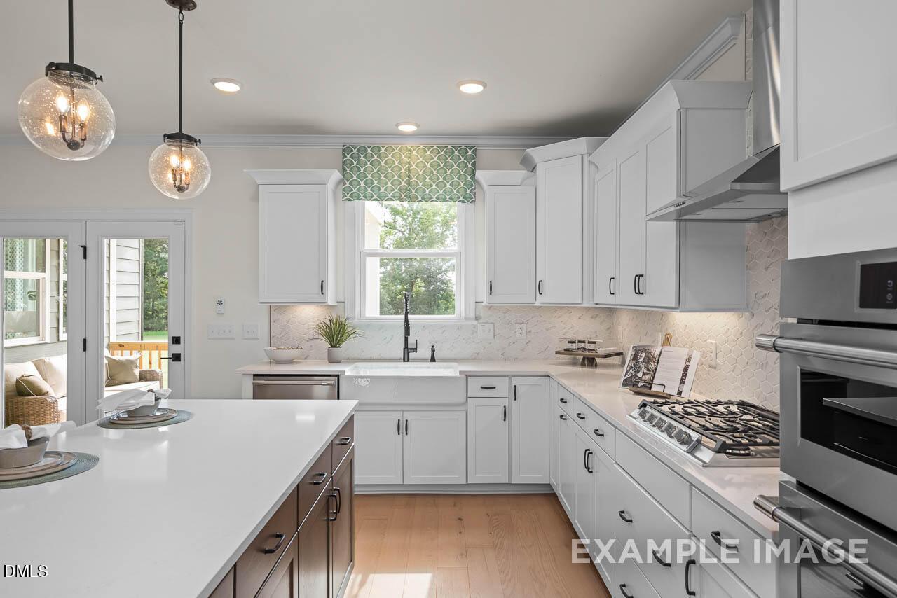Modern white kitchen with shaker cabinets, quartz island, farmhouse sink, and stainless range in Davidson Homes Crawford D, Angier, NC