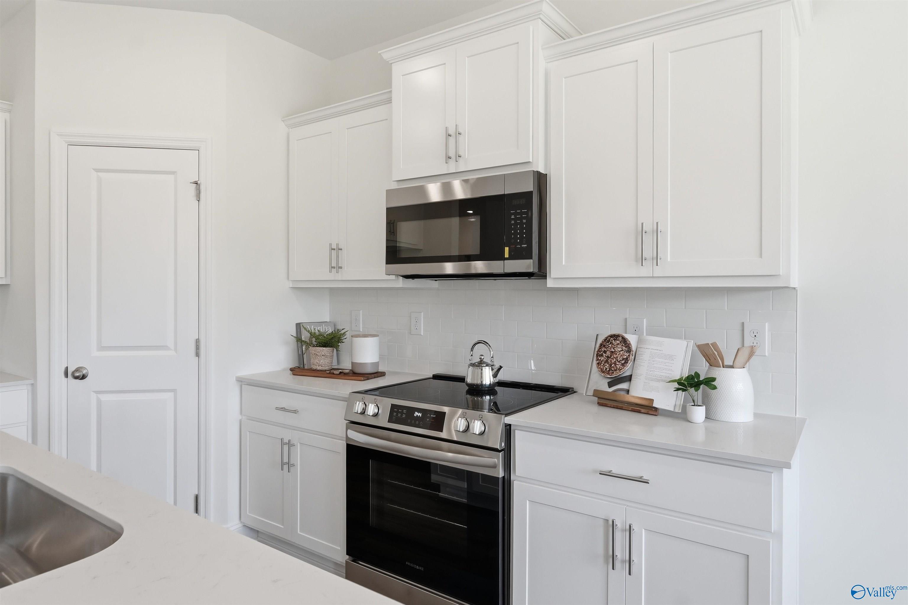 Modern kitchen with white shaker cabinets, subway tile backsplash, and stainless appliances in The Franklin C floor plan.
