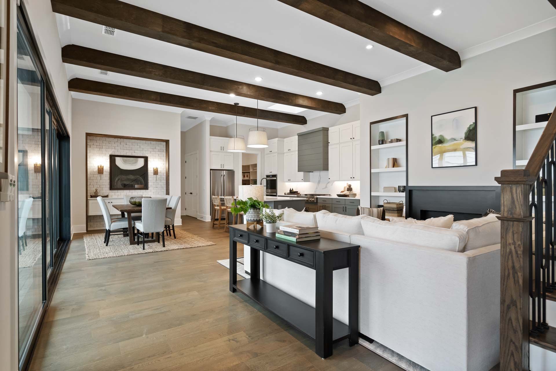 Open-concept kitchen and living area at Manor Estates in Marietta GA with exposed wood beams, hardwood floors, and modern dining setup
