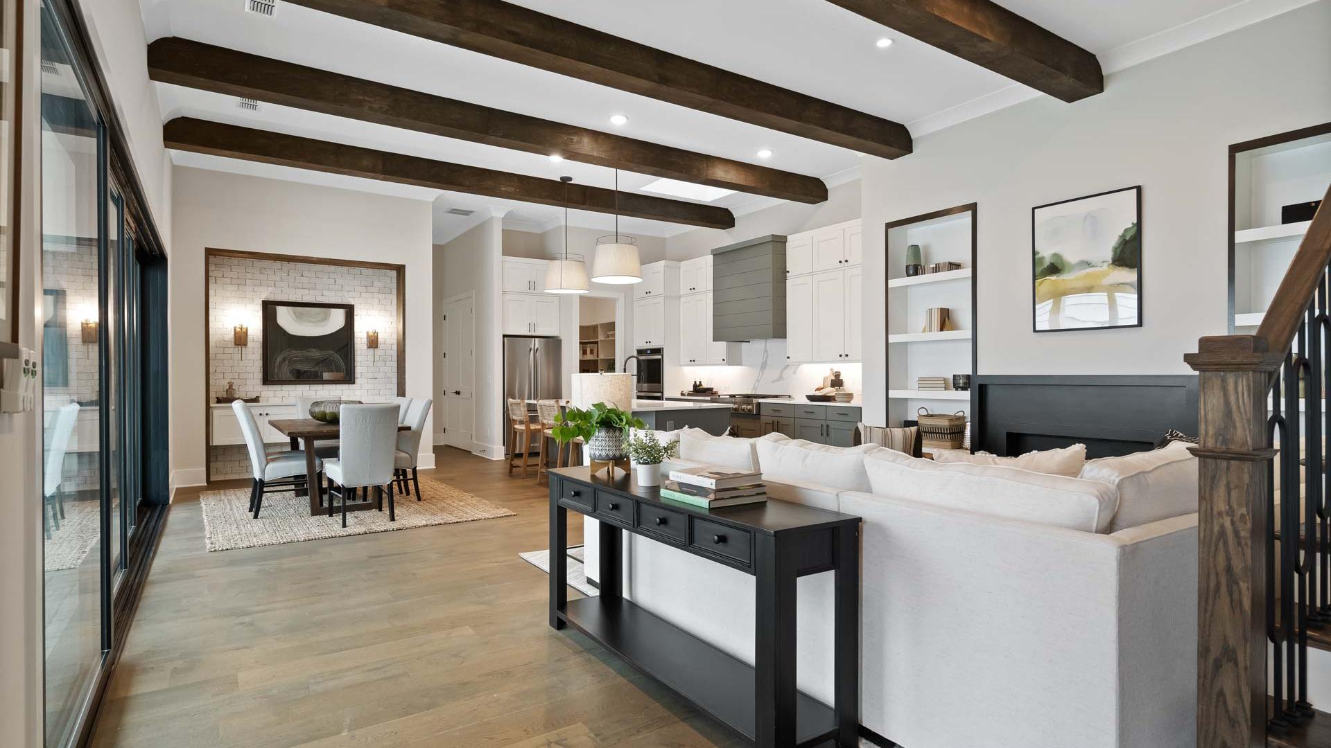 Open-concept kitchen and living area at Manor Estates in Marietta GA with exposed wood beams, hardwood floors, and modern dining setup
