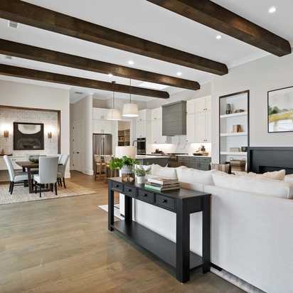 Open-concept kitchen and living area at Manor Estates in Marietta GA with exposed wood beams, hardwood floors, and modern dining setup