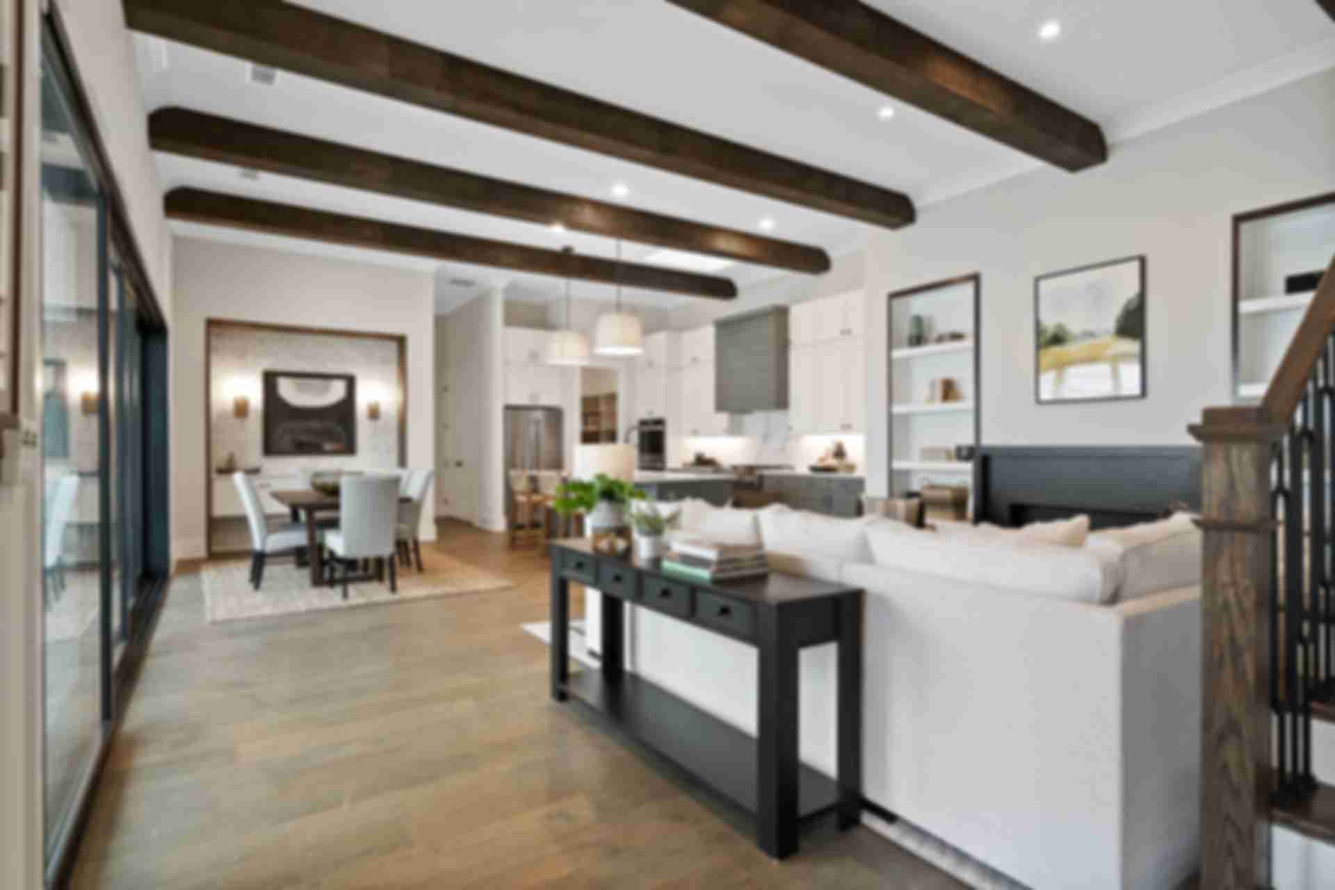 Open-concept kitchen and living area at Manor Estates in Marietta GA with exposed wood beams, hardwood floors, and modern dining setup