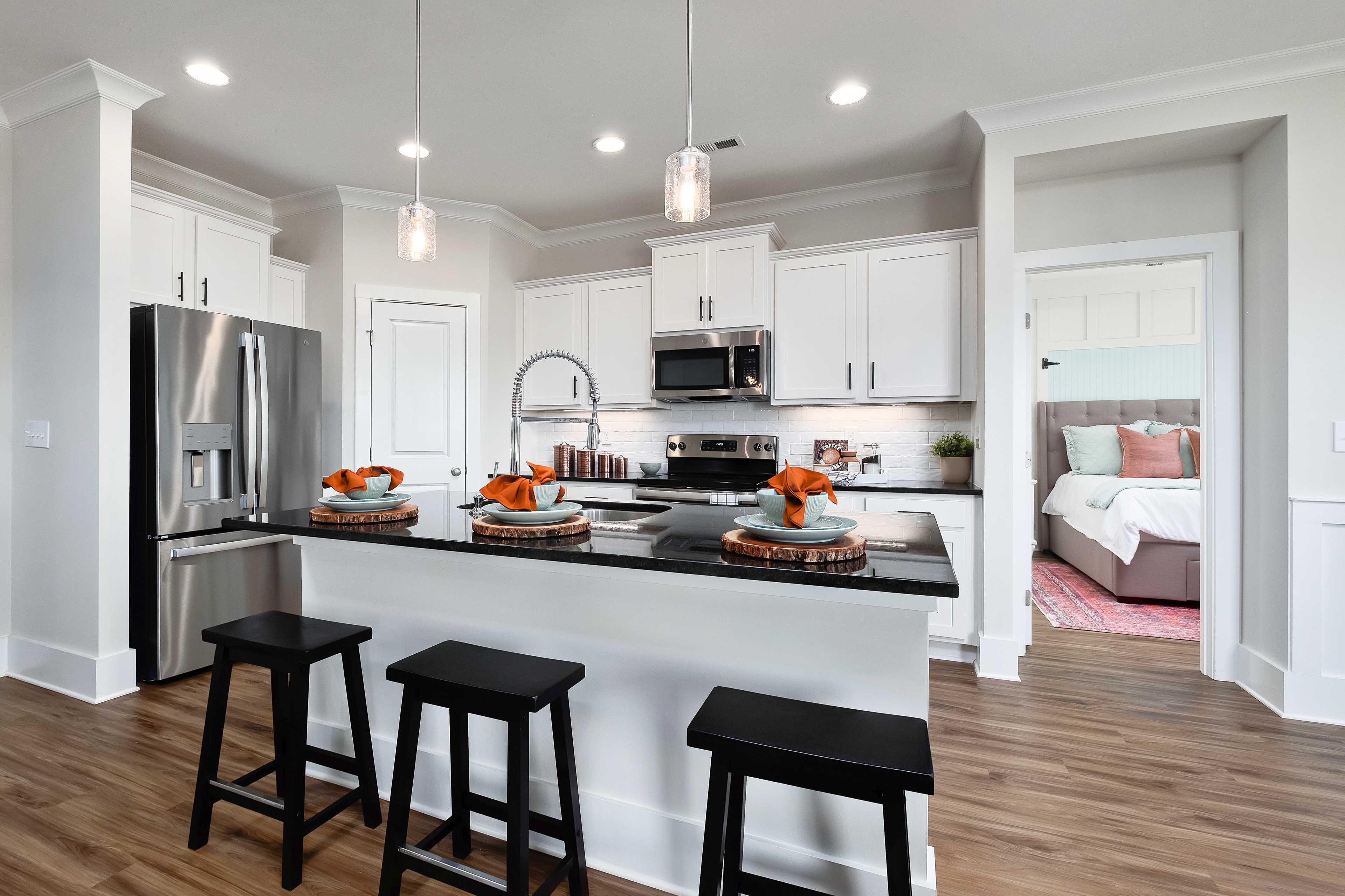 Modern kitchen with white cabinets, black island, and bedroom view at Mallard Landing in Athens, Alabama