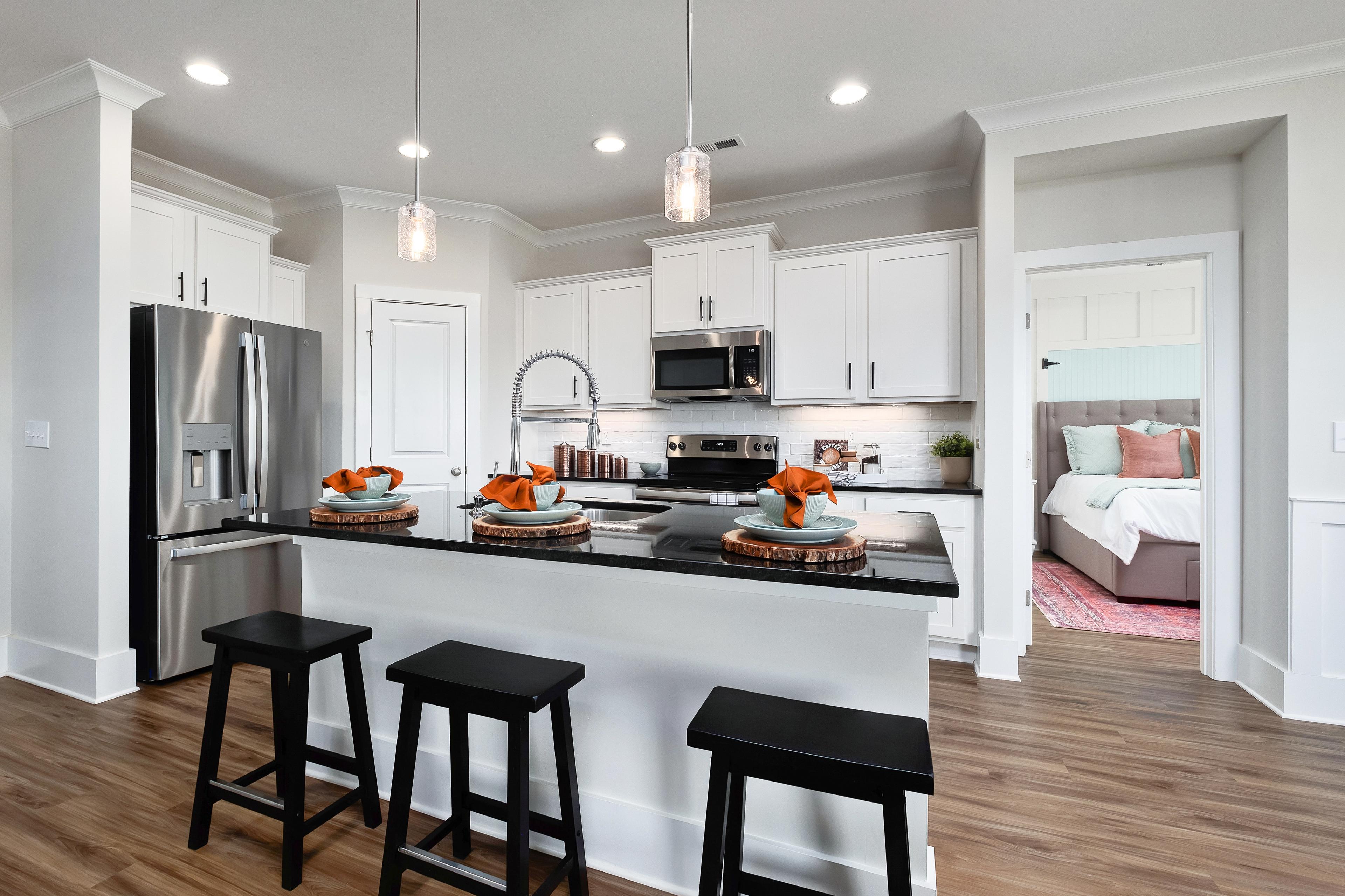 Modern kitchen with white cabinets, black island, and bedroom view at Mallard Landing in Athens, Alabama