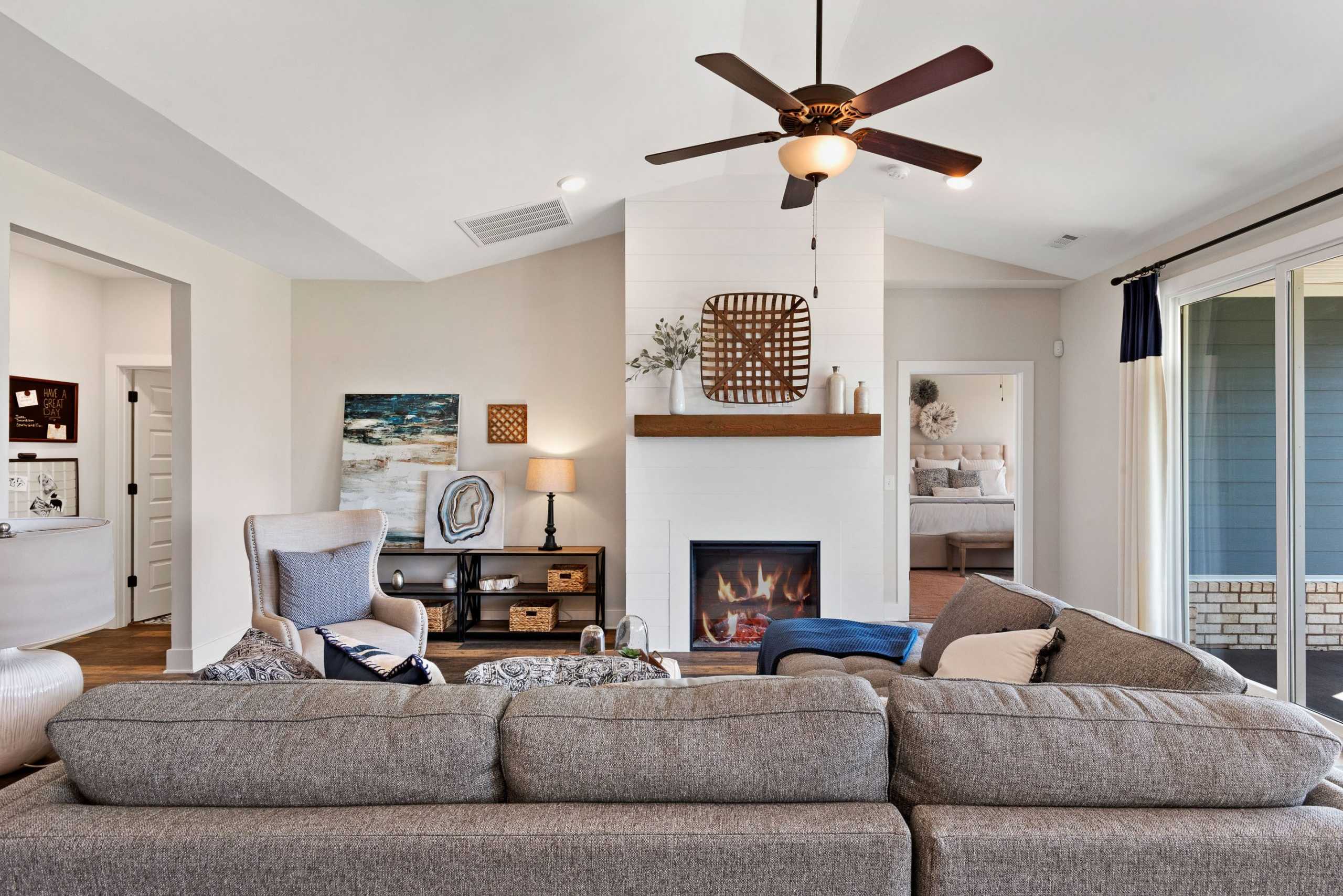 Cozy open-concept living room at Rivers Edge in Murfreesboro TN with white brick fireplace, gray sectional sofa, and ceiling fan