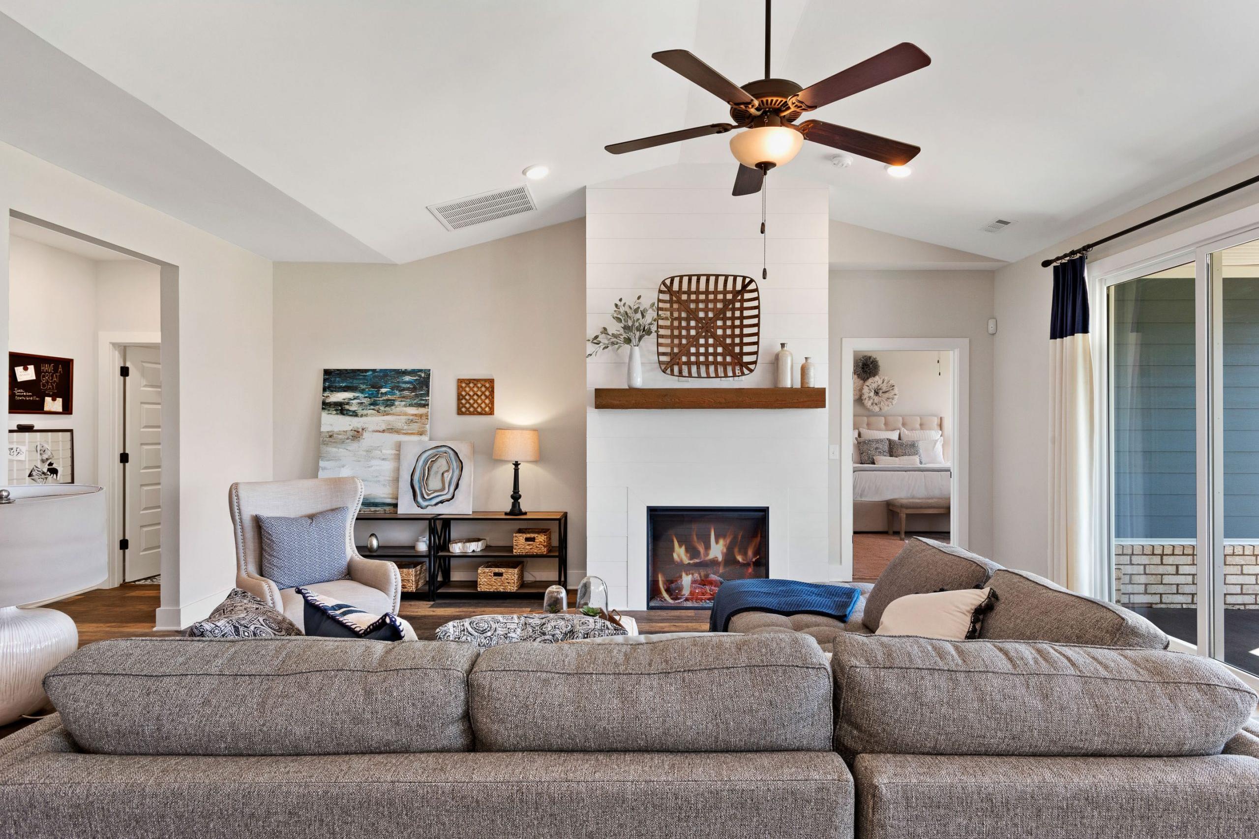 Cozy open-concept living room at Rivers Edge in Murfreesboro TN with white brick fireplace, gray sectional sofa, and ceiling fan