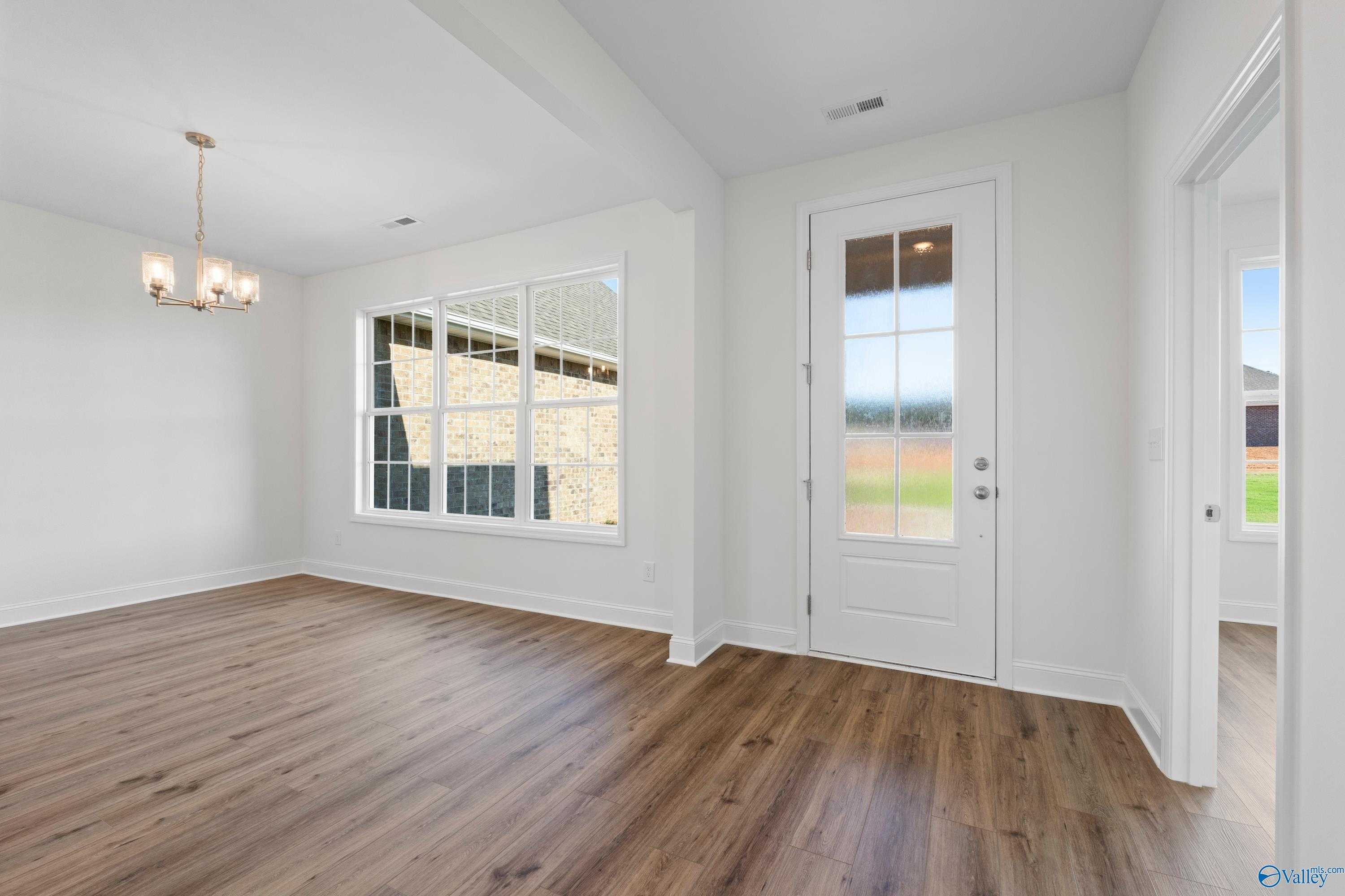 Bright dining room with hardwood floors, chandelier lighting, and large windows overlooking backyard in Davidson Homes The Oxford, Harvest AL