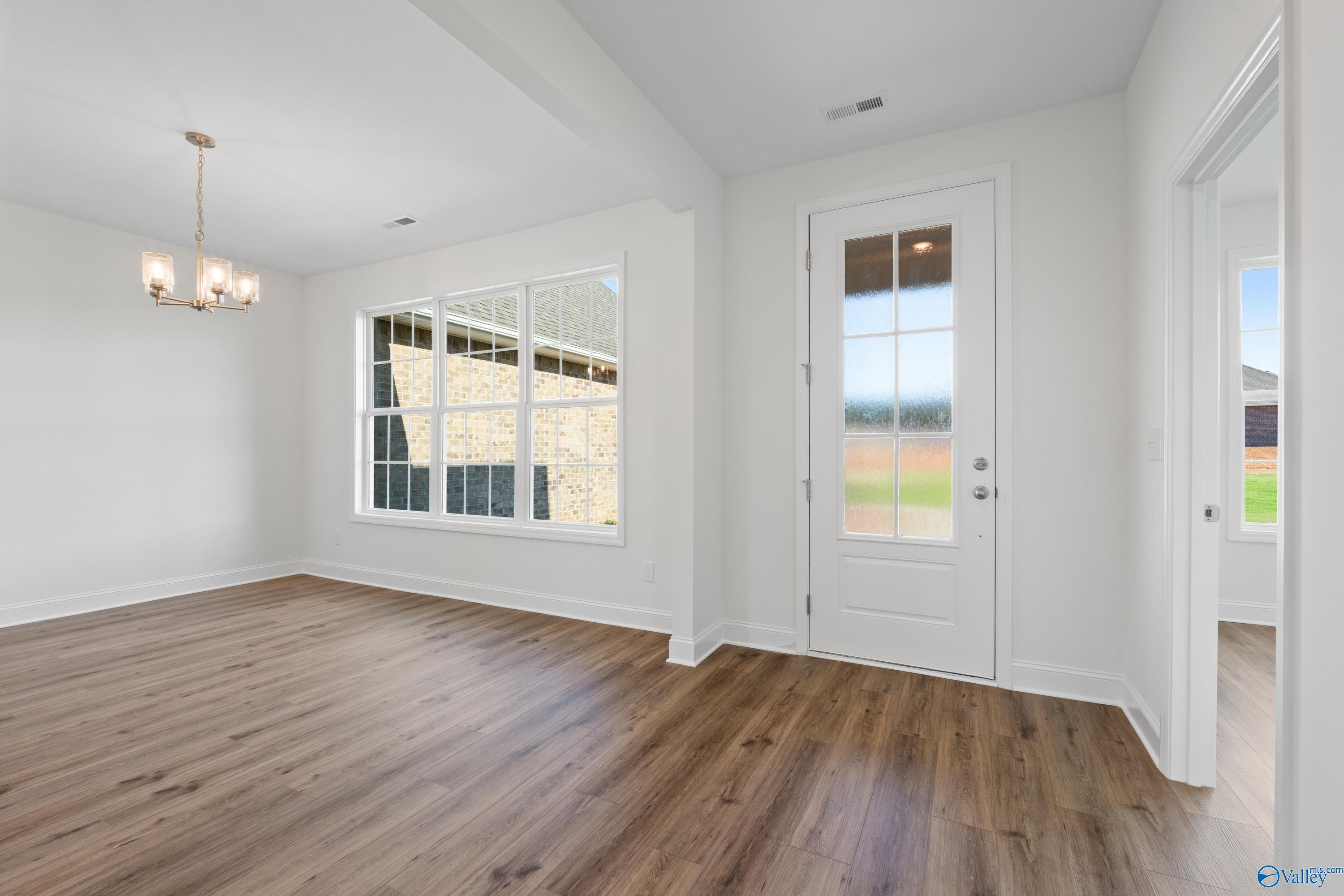 Bright dining room with hardwood floors, chandelier lighting, and large windows overlooking backyard in Davidson Homes The Oxford, Harvest AL