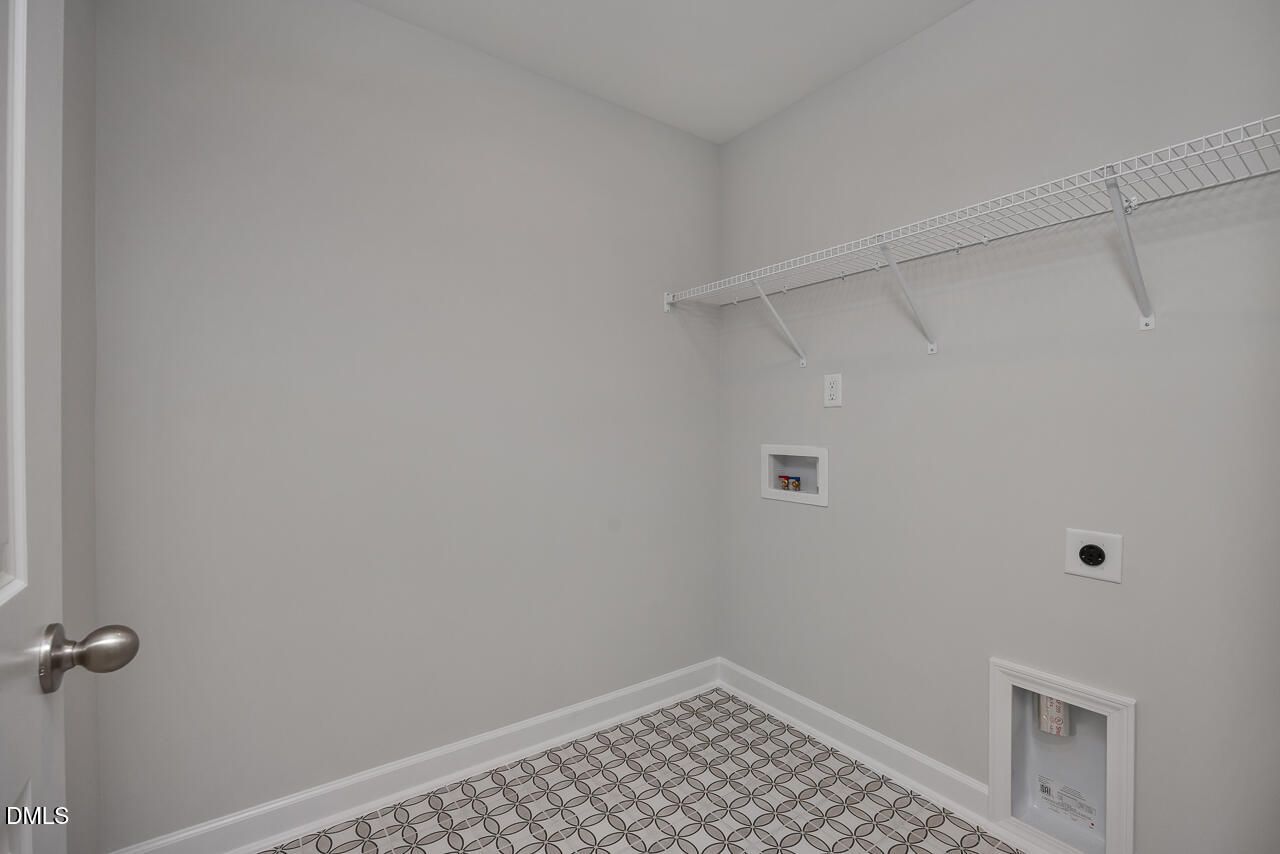 Laundry room with patterned tile flooring and storage shelving in The Mitchell floor plan at Camden Park, Knightdale, NC.