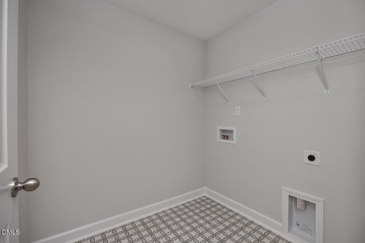 Laundry room with patterned tile flooring and storage shelving in The Mitchell floor plan at Camden Park, Knightdale, NC.