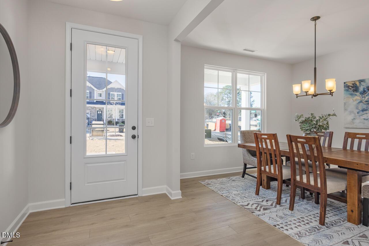 Elegant dining room with wooden table, upholstered chairs, chandelier, and garden views in Davidson Homes The Ash B, Lillington, NC