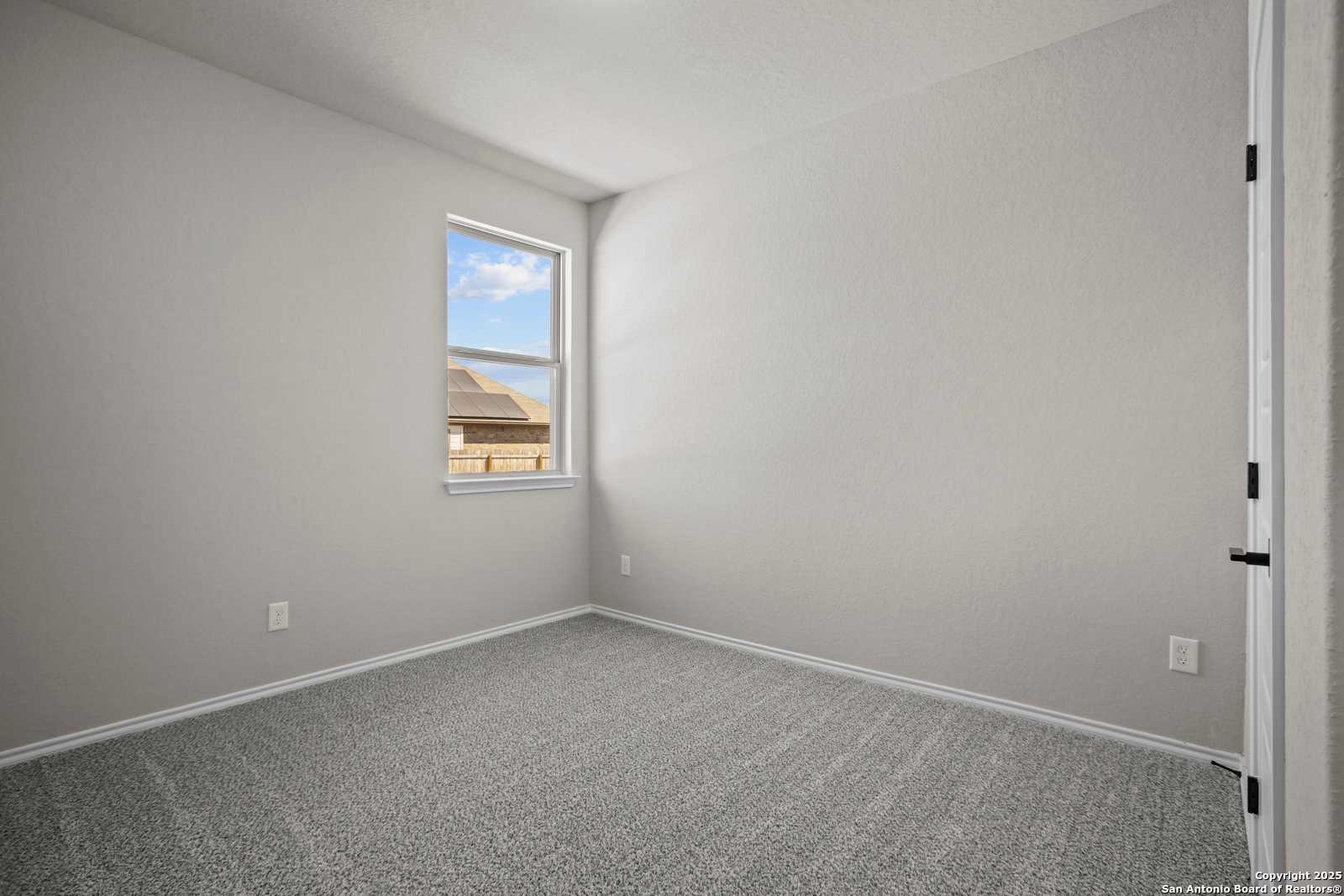 Bright secondary bedroom with neutral gray walls, plush carpet, and large window in Davidson Homes The Asheville E, Converse, Texas