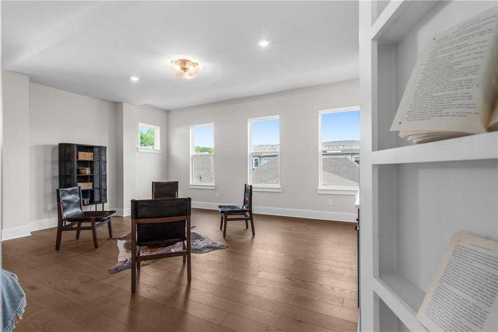 Bright sitting room with large windows, hardwood floors, and bookshelves in Davidson Homes The Seaside B, Woodstock, GA