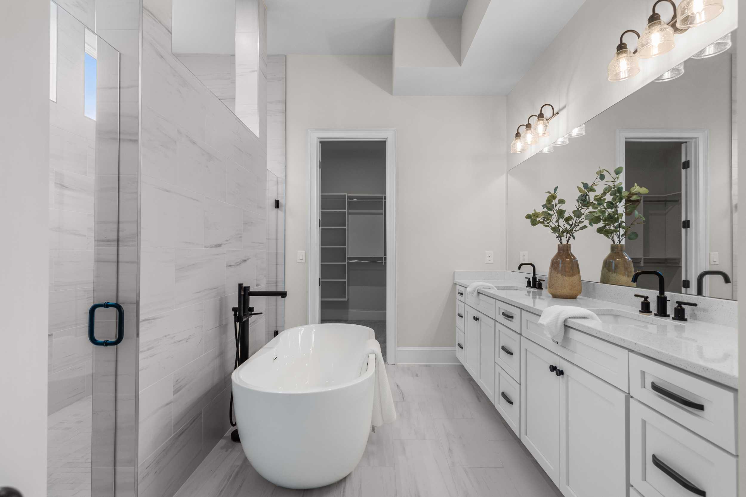 Luxury primary bathroom at The Village at Towne Lake in Woodstock GA with freestanding tub, double vanity, and glass shower