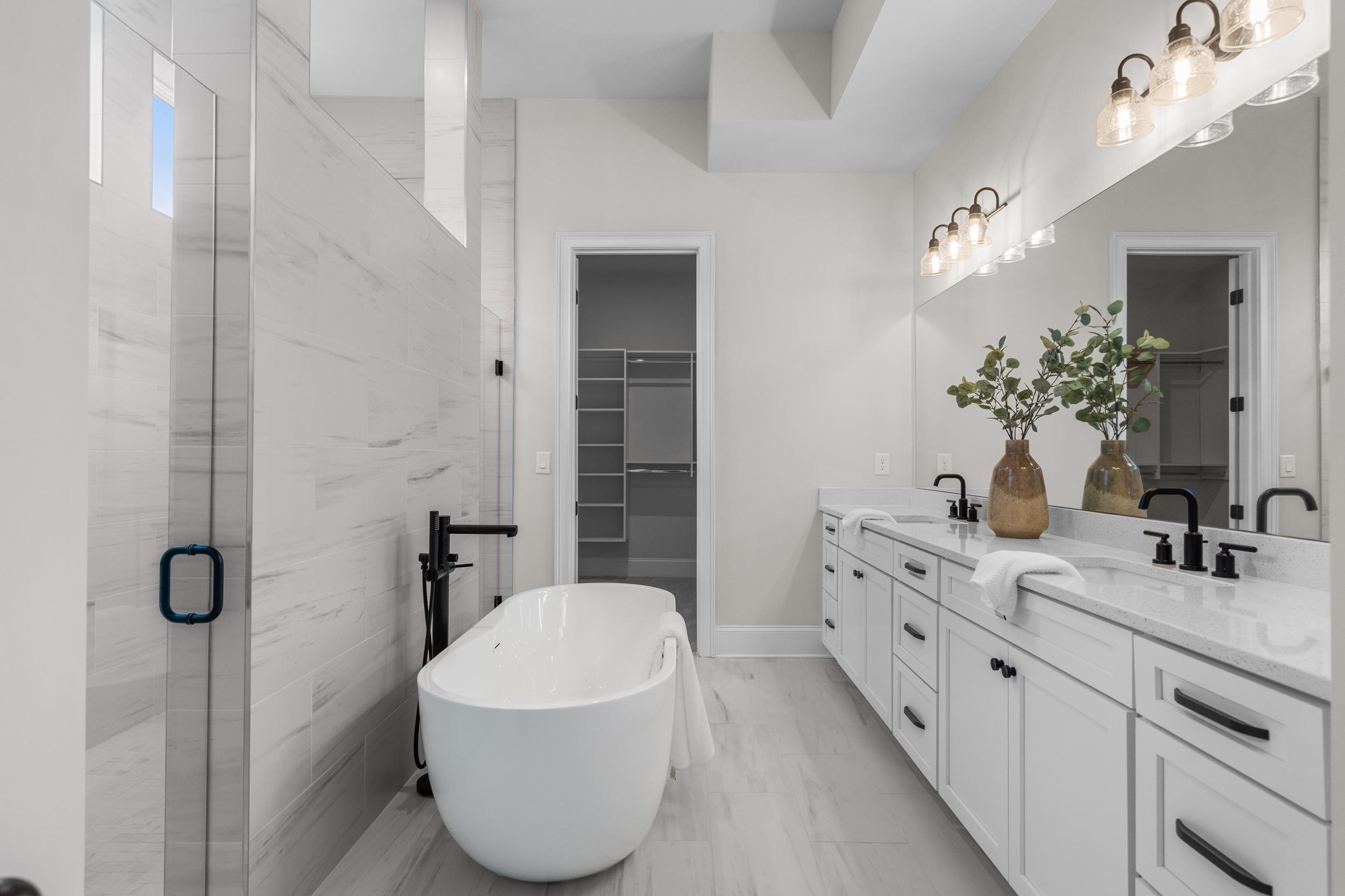 Luxury primary bathroom at The Village at Towne Lake in Woodstock GA with freestanding tub, double vanity, and glass shower