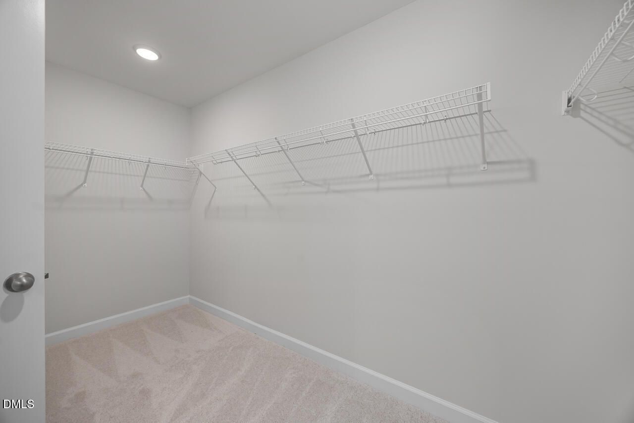 Spacious walk-in closet with white wire shelving and beige carpet in Davidson Homes The Gavin B, Gregory Village, Lillington, NC