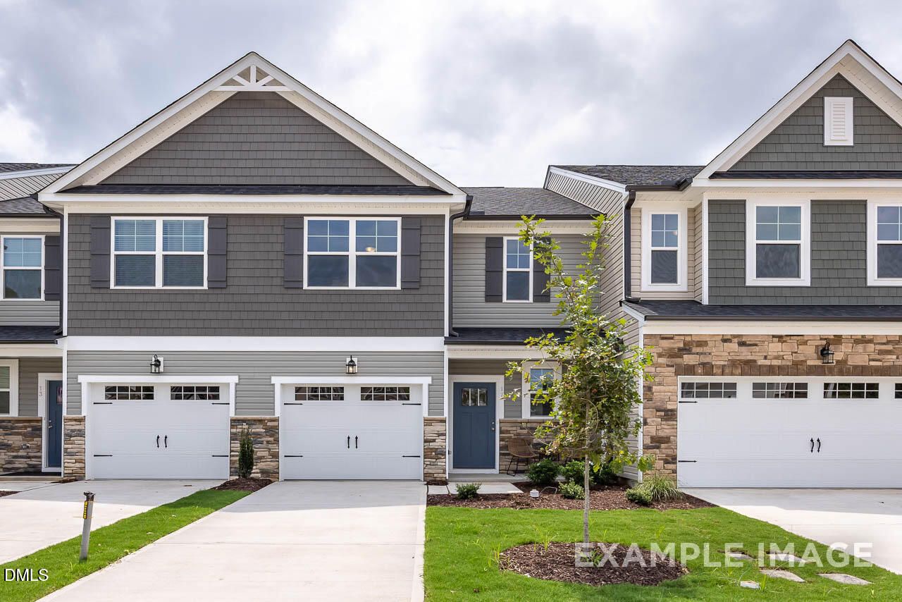 Modern two-story townhomes with gray siding, brick accents, garages, and landscaped front yard in Springvale, Fuquay-Varina, NC by Davidson Homes