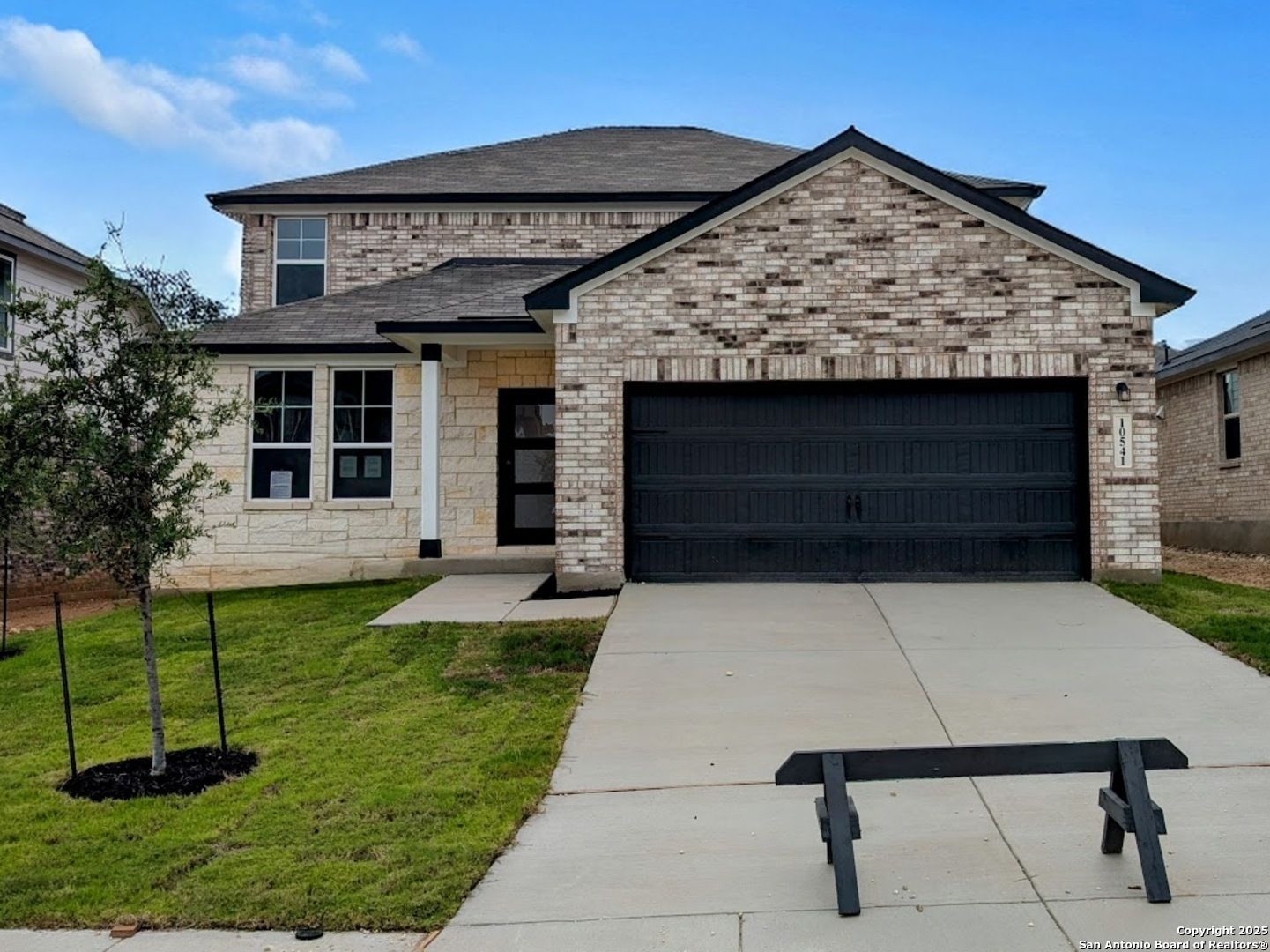 Modern two-story brick home with black 2-car garage, driveway, and lush front lawn in Bricewood, San Antonio, Texas - Davidson Homes Douglas F