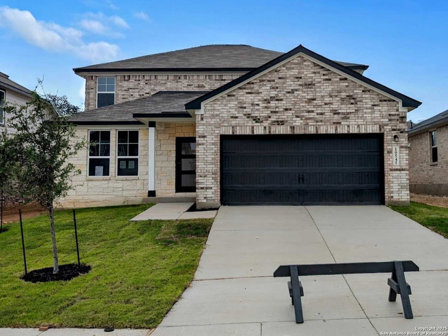 Modern two-story brick home with black 2-car garage, driveway, and lush front lawn in Bricewood, San Antonio, Texas - Davidson Homes Douglas F