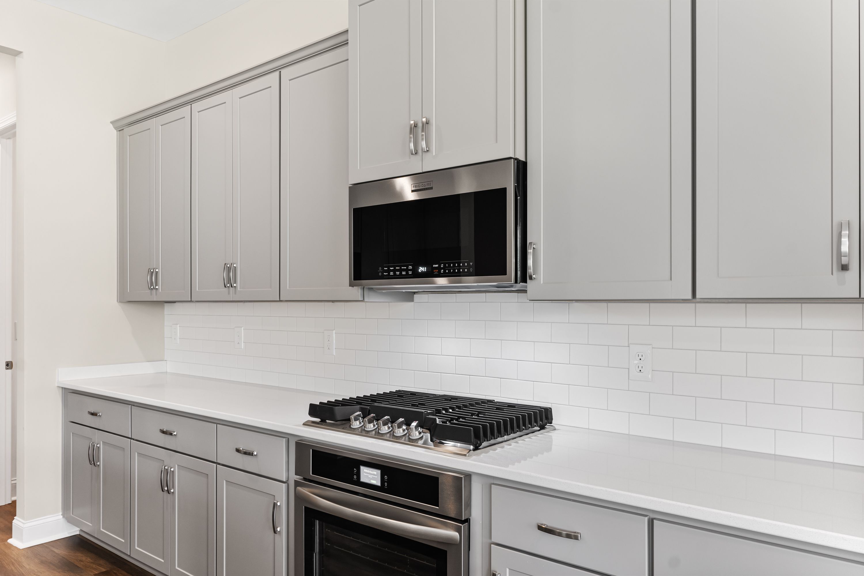 Modern kitchen in The Arcadia E with gray shaker cabinets, white subway tile backsplash, and stainless steel gas range