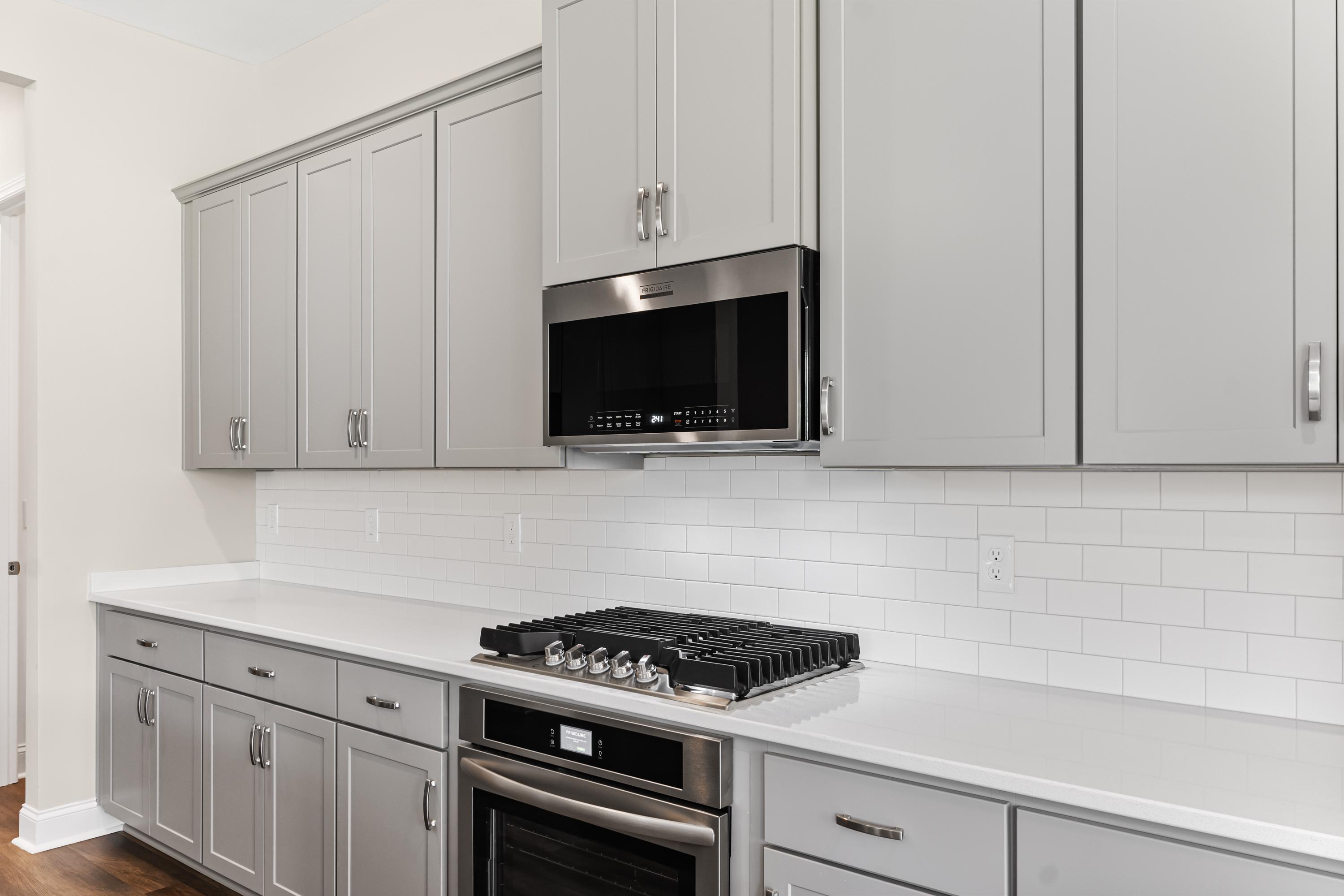 Modern kitchen in The Arcadia B with gray shaker cabinets, gas cooktop, stainless steel appliances, and white subway tile backsplash