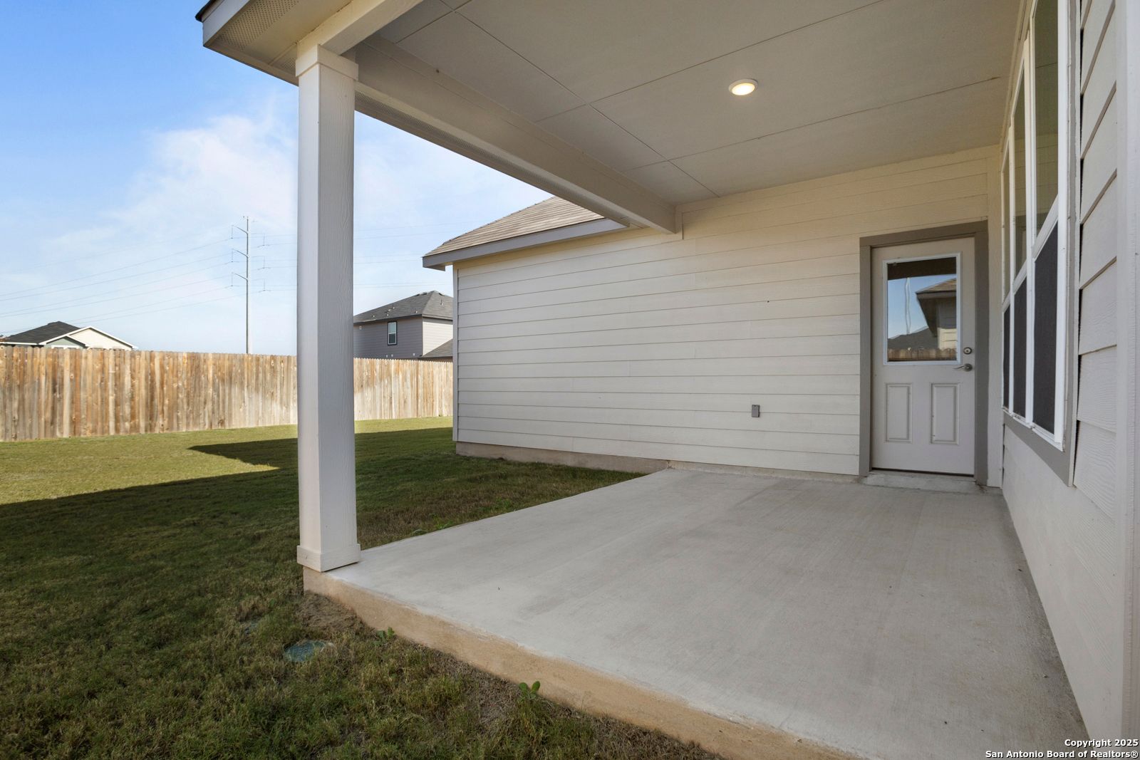 Covered back patio with concrete slab, glass door, and fenced yard in Davidson Homes The Collin B, Hannah Heights, Seguin, Texas