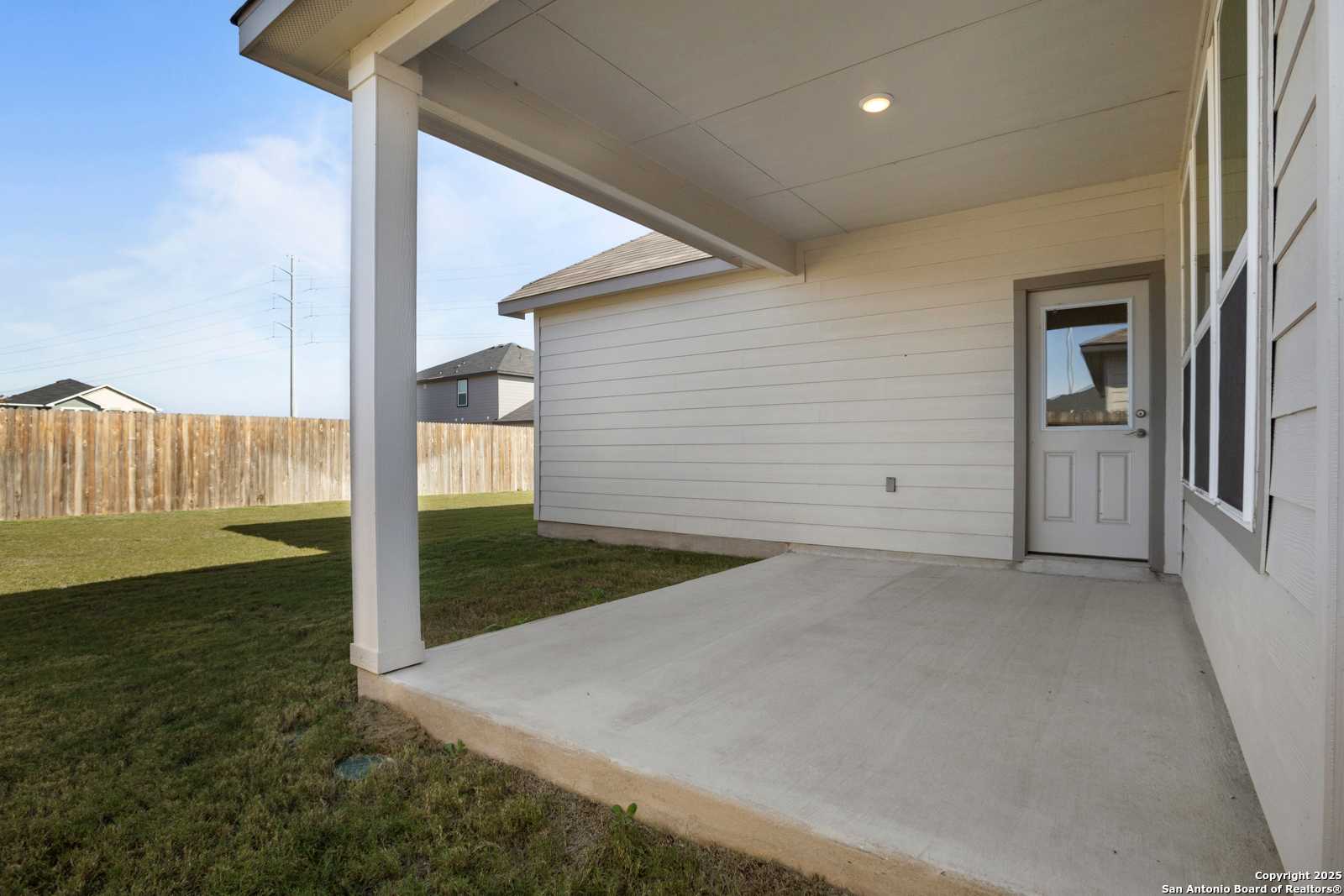 Covered back patio with concrete slab, glass door, and fenced yard in Davidson Homes The Collin B, Hannah Heights, Seguin, Texas