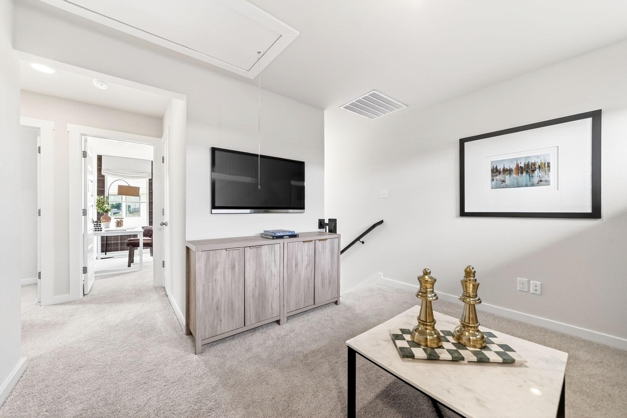 Cozy loft living area at Mesa Vista in San Antonio with wall-mounted TV, wooden console, and modern decor.
