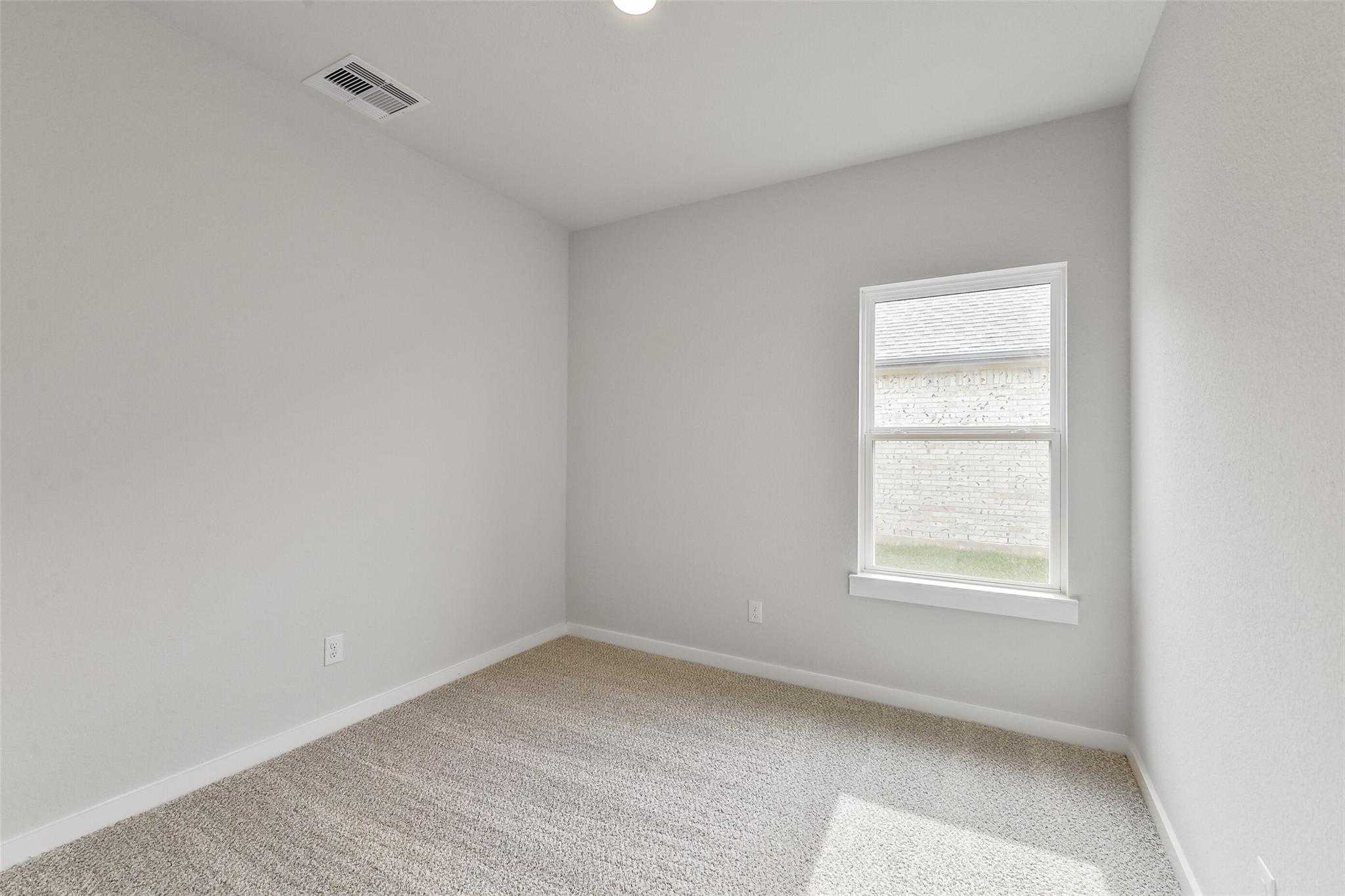 Bright secondary bedroom featuring light gray walls, beige carpet, and large window in Davidson Homes The Colorado G, Magnolia, Texas