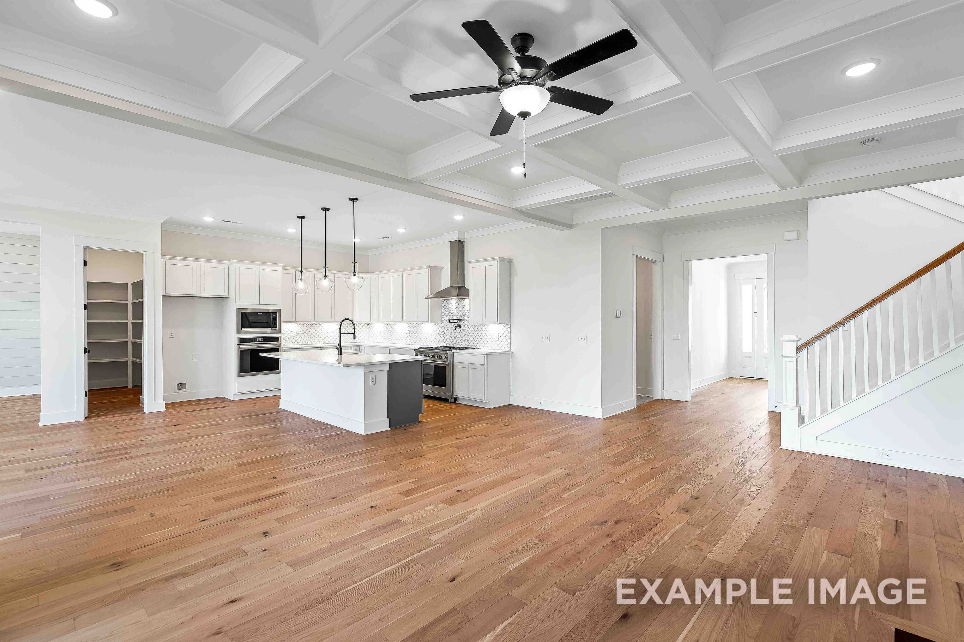 Spacious open-concept kitchen in The Albany A with white cabinets, gray island, pendant lights, and hardwood floors