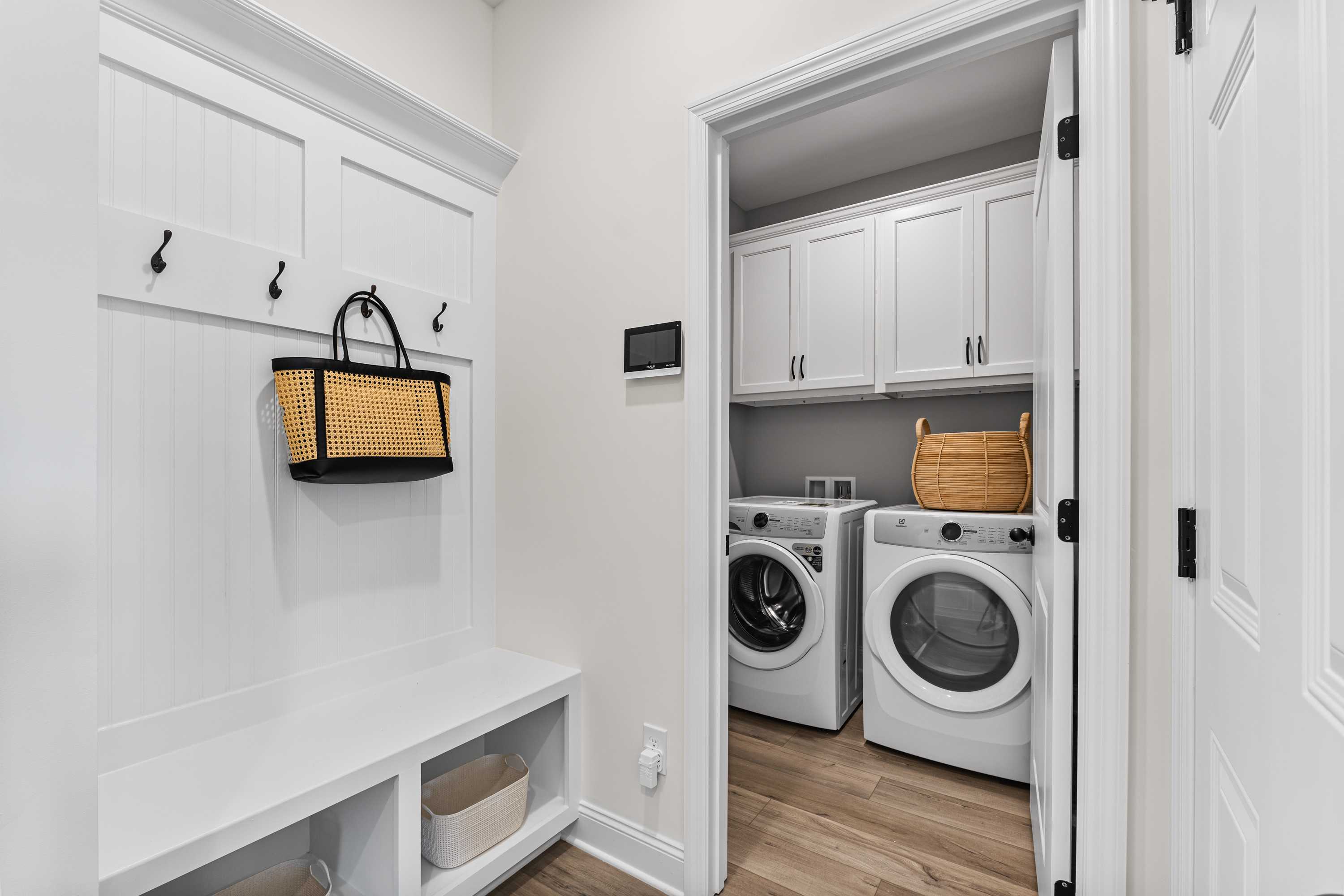 Spacious mudroom laundry combo in Lynn Meadows Meridianville AL home with white shaker cabinets bench hooks and washer dryer