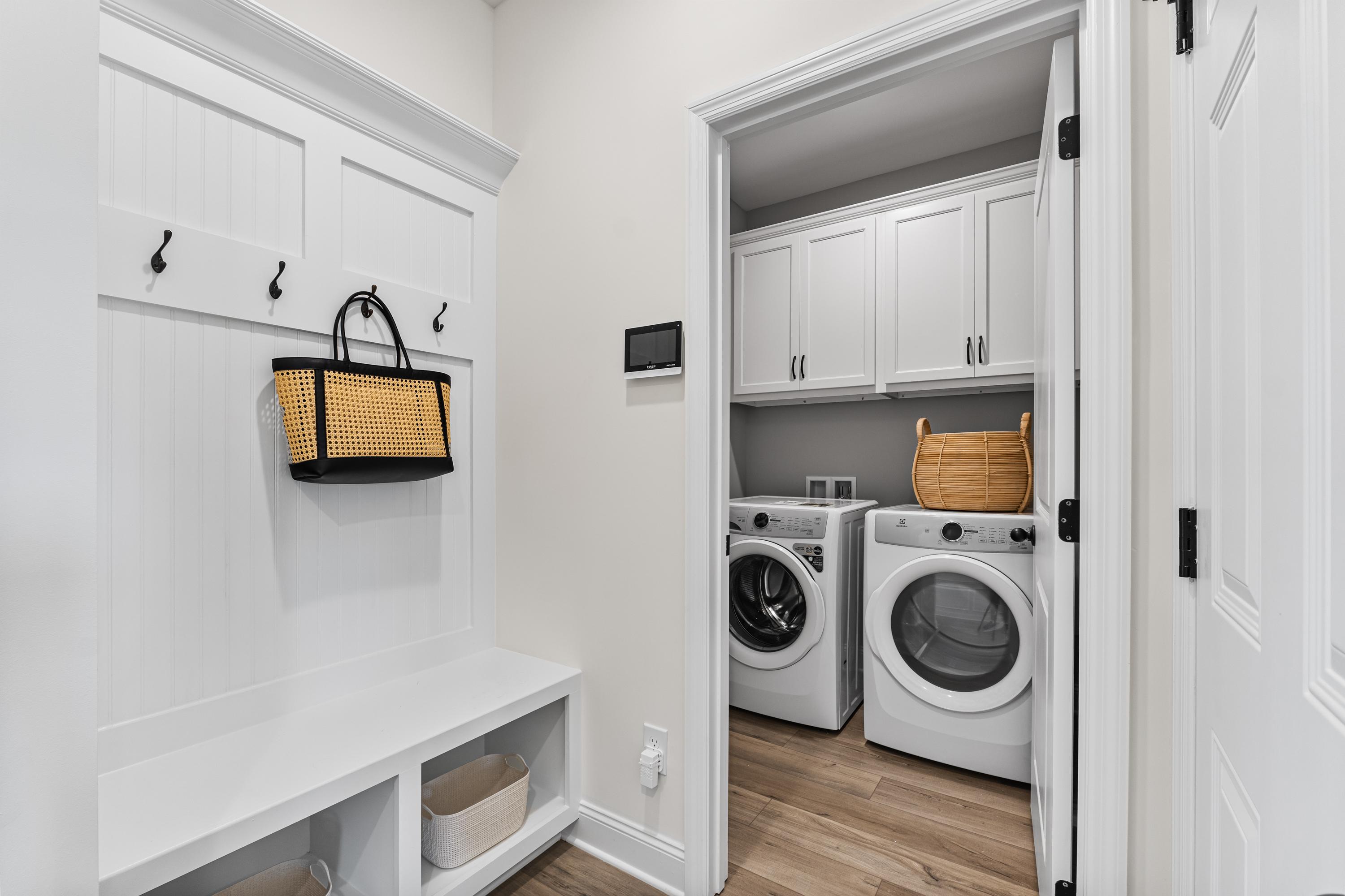 Spacious mudroom laundry combo in Lynn Meadows Meridianville AL home with white shaker cabinets bench hooks and washer dryer