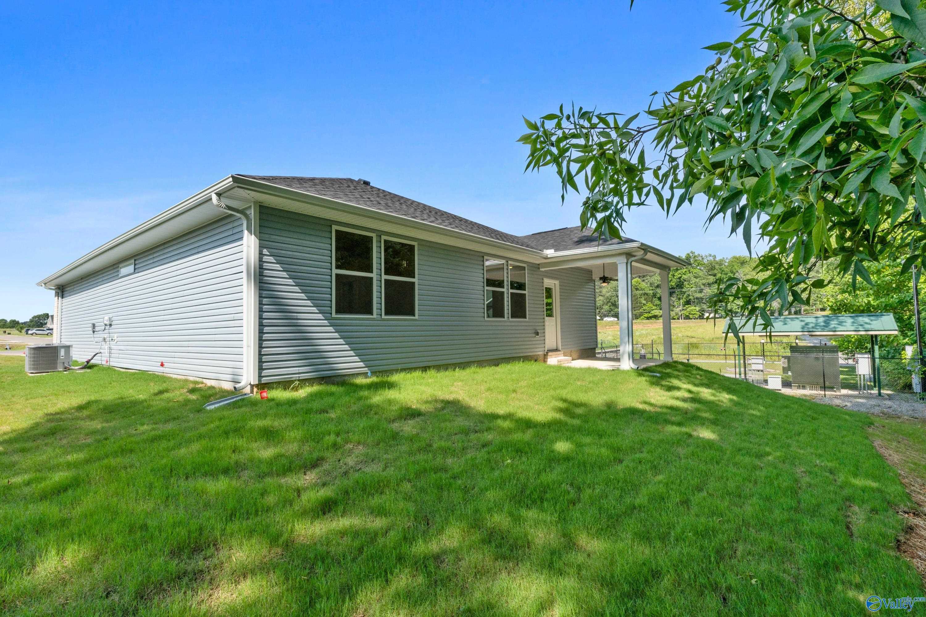 Side view of single-story gray home with covered porch, large windows, and lush green yard in Bailey Park, Fayetteville, Tennessee