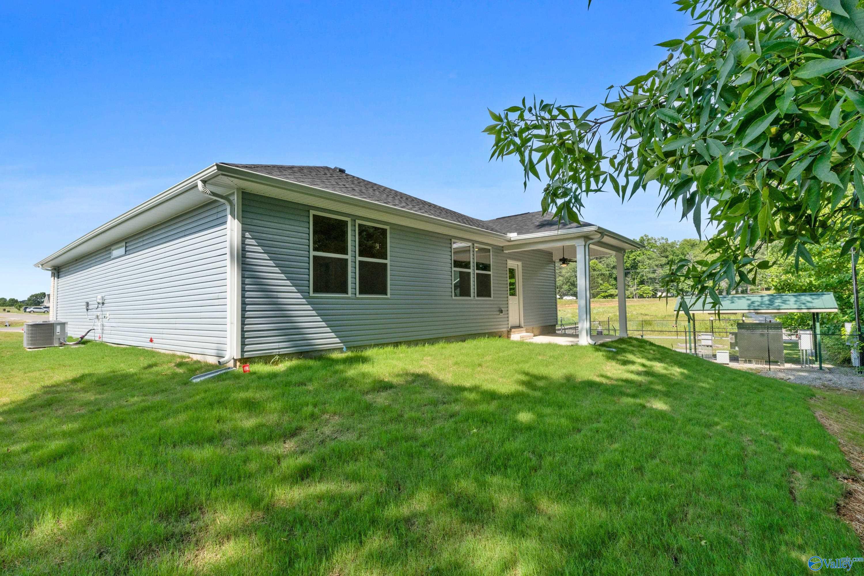 Side view of The Polaris single-story home with gray siding, covered porch, 2-car garage, and lush green lawn in Bailey Park, Fayetteville, Tennessee