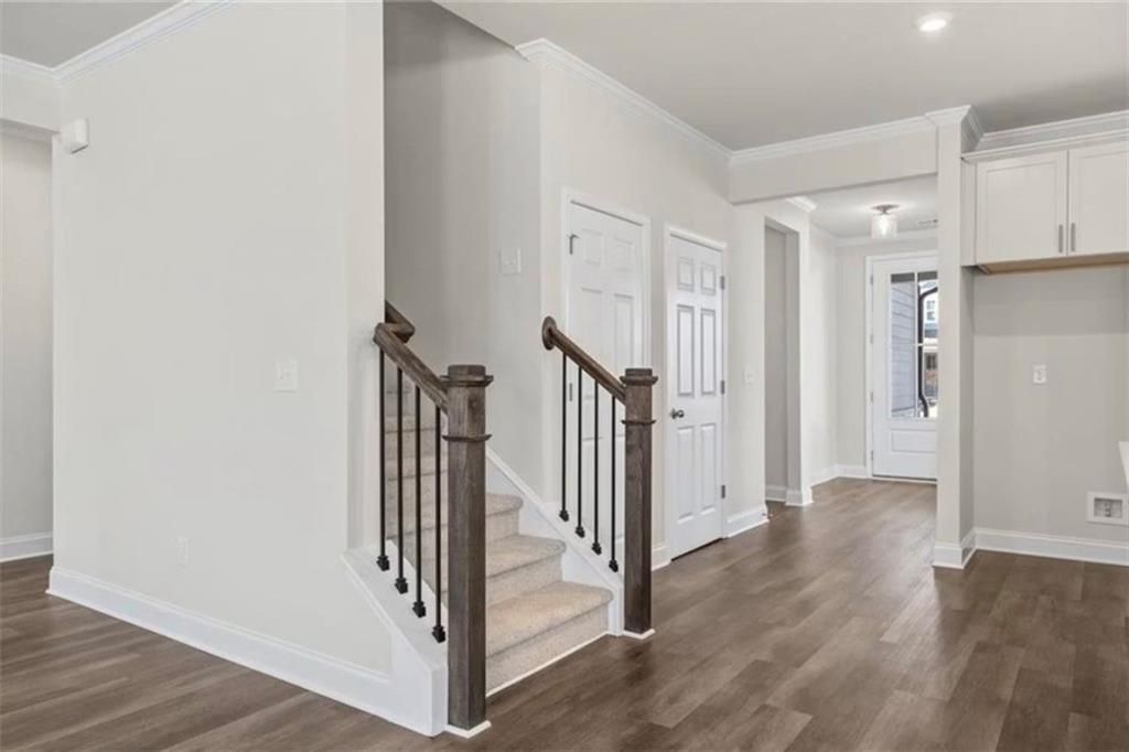 Foyer and carpeted staircase with wood railing in The Ash C floor plan at Wehunt Meadows, Hoschton, Georgia.