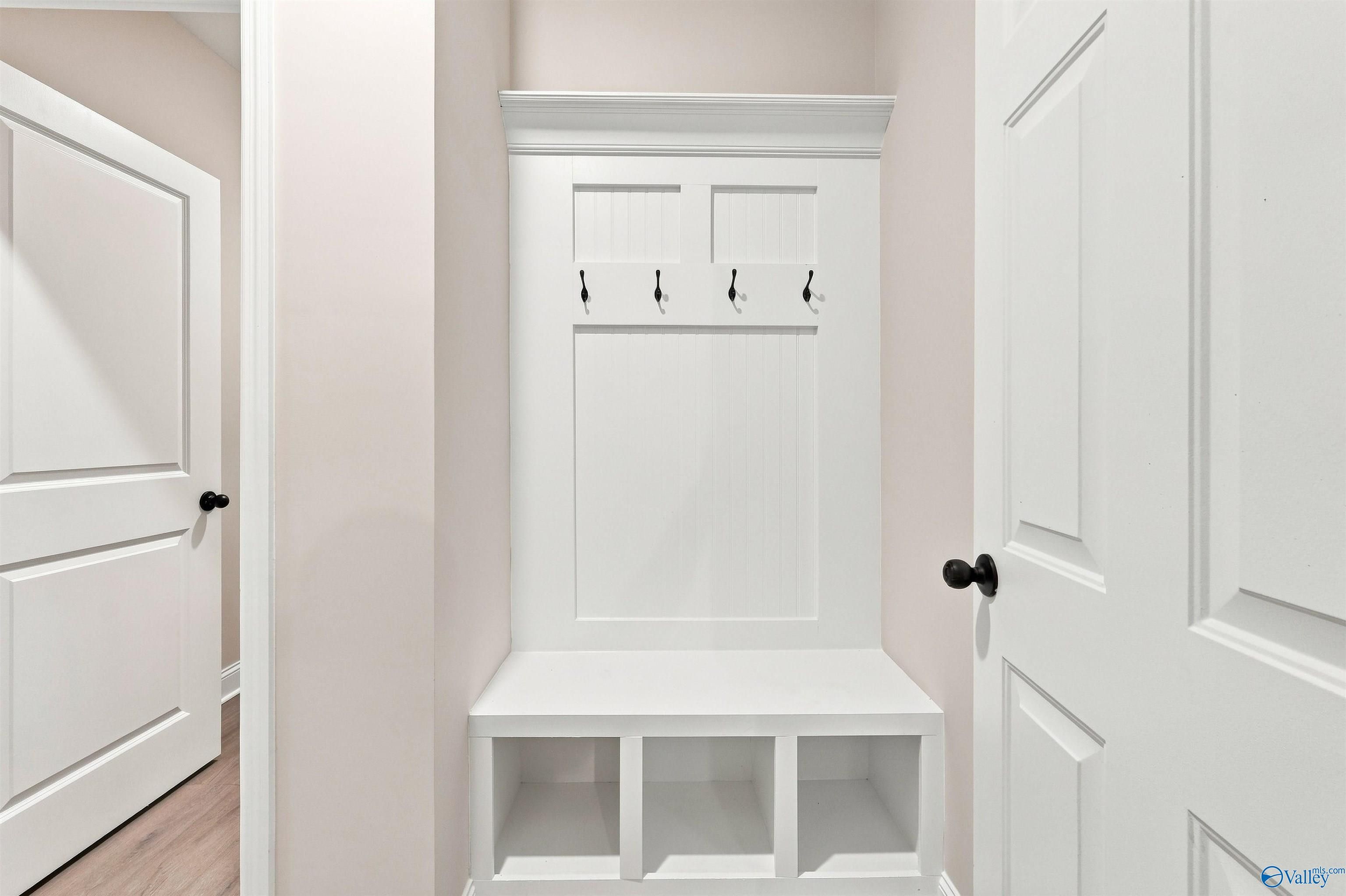 Built-in white mudroom bench with coat hooks in The Daphne floor plan at Spragins Cove in Huntsville, Alabama.