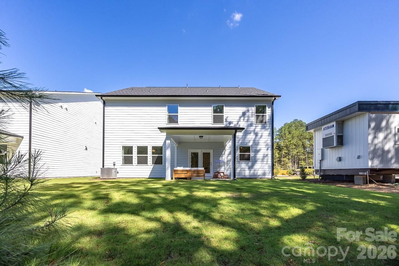 Two-story white Davidson Homes Hickory C II with covered back patio and spacious fenced backyard in Enclave at Belmont, NC