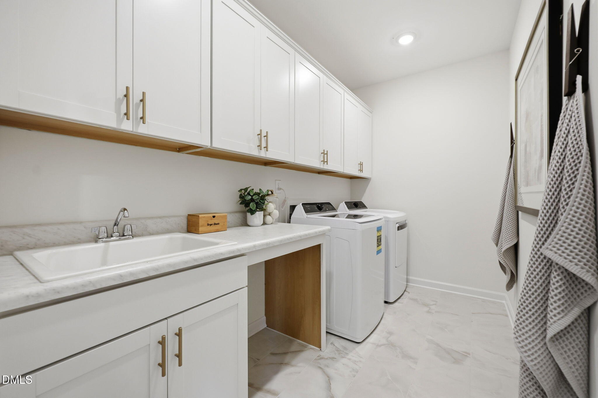 Laundry room with white cabinets, utility sink, and washer-dryer in The Aspen B by Davidson Homes in Wendell, NC.