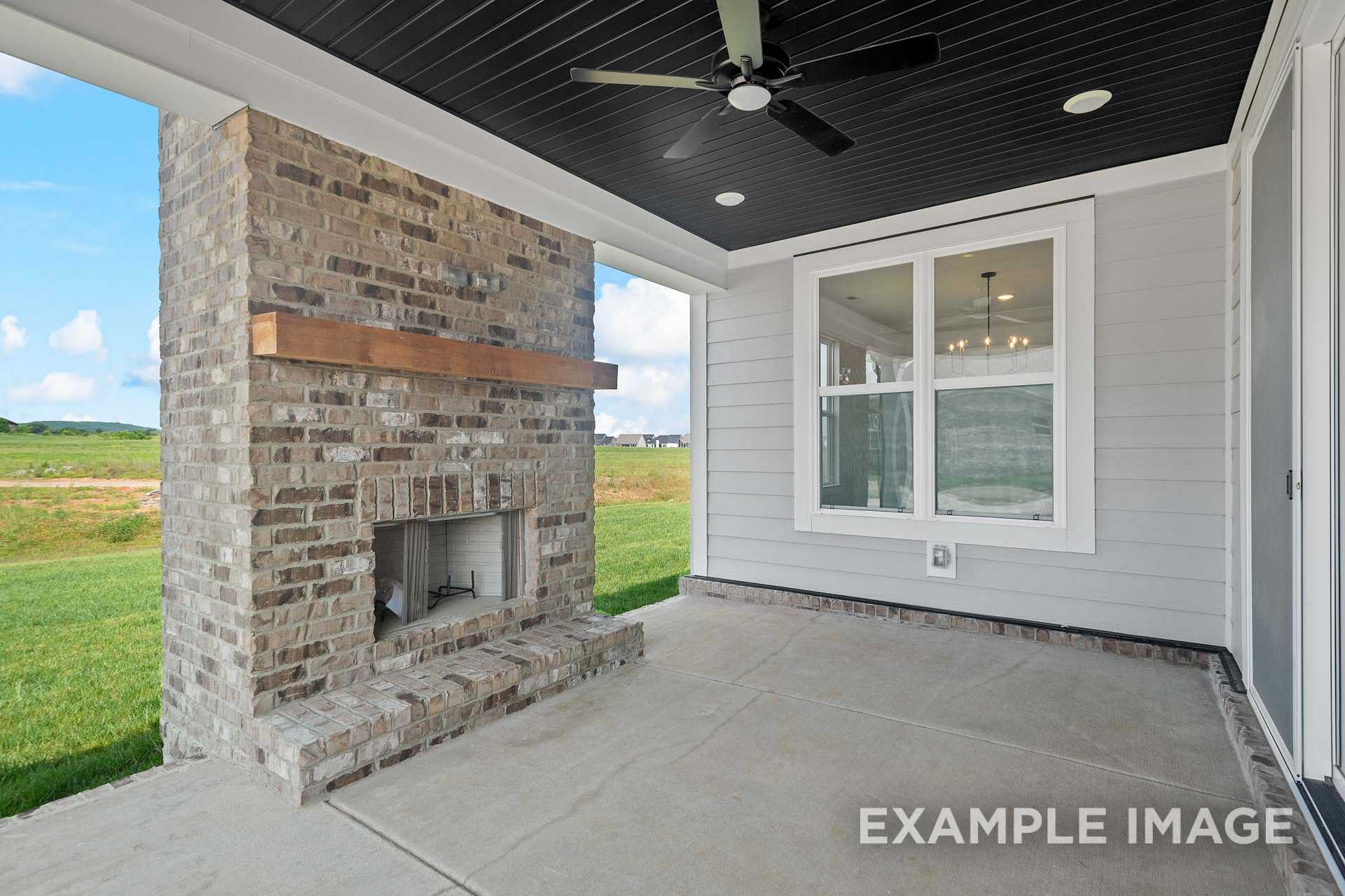 Covered patio in The Hathaway Davidson Homes design featuring brick fireplace, wooden beam mantel, ceiling fan, and lush yard view