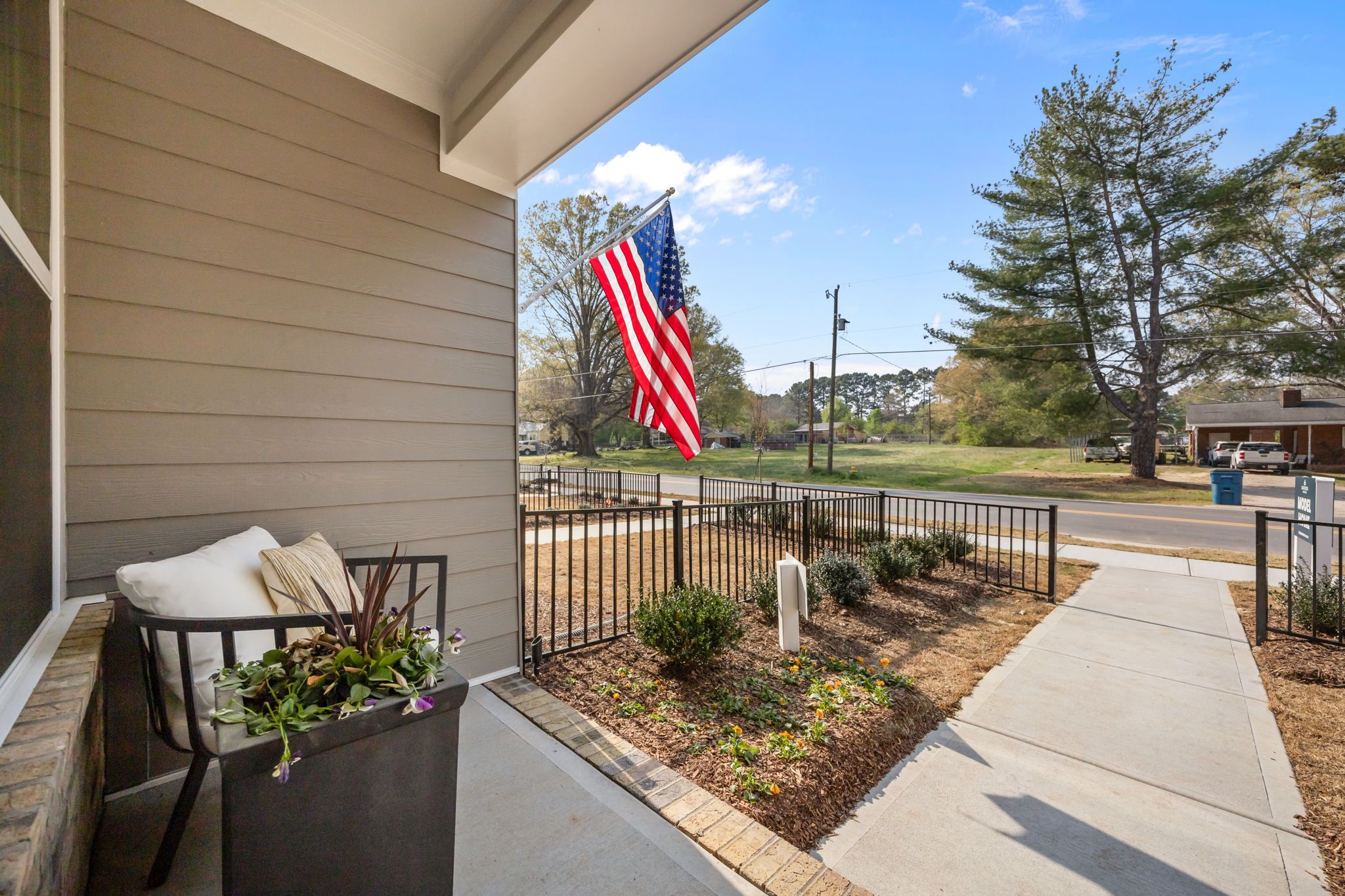 Front porch view of The Mitchell in Knightdale, NC featuring cozy seating, landscaping, and an American flag.