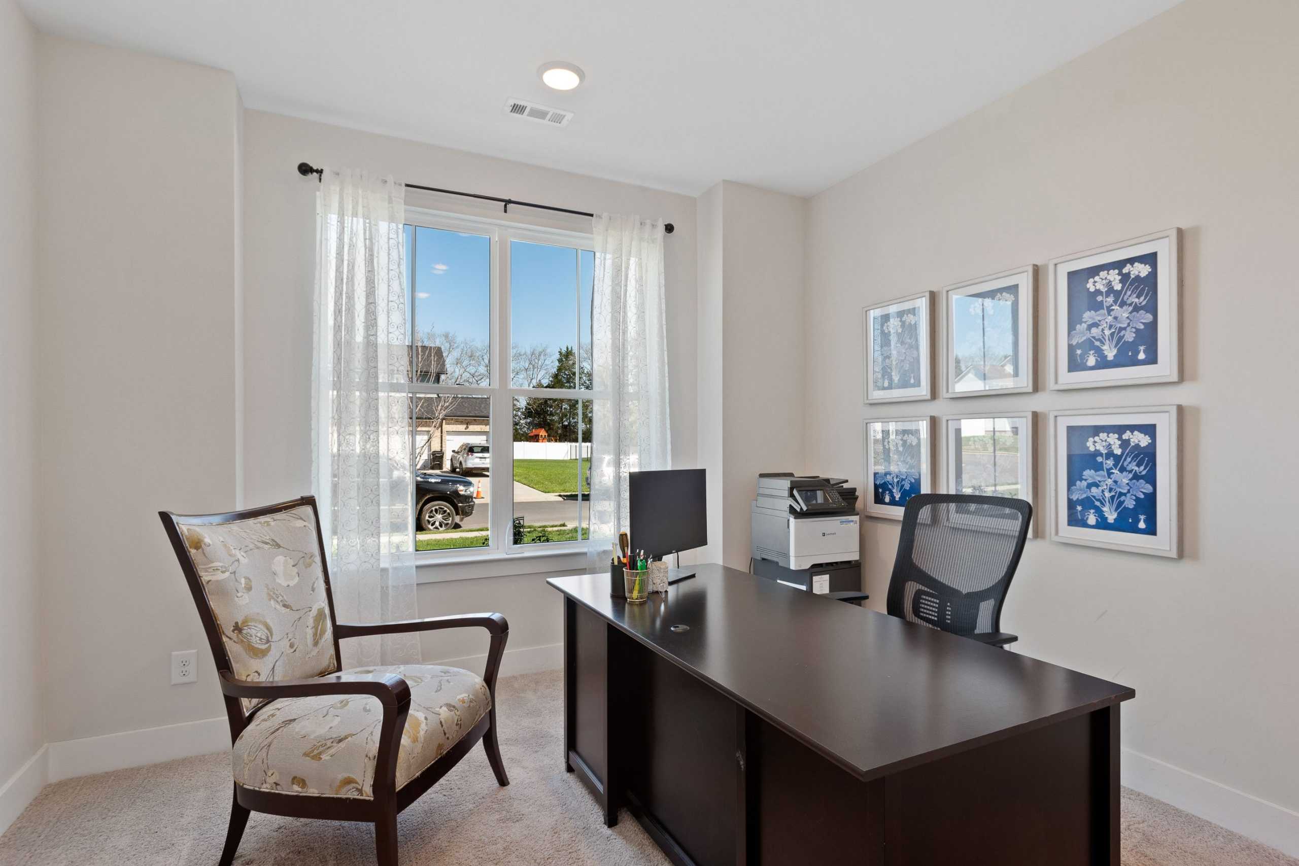Cozy home office at Rivers Edge in Murfreesboro TN with beige walls, dark wood desk, ergonomic chair, and large window view