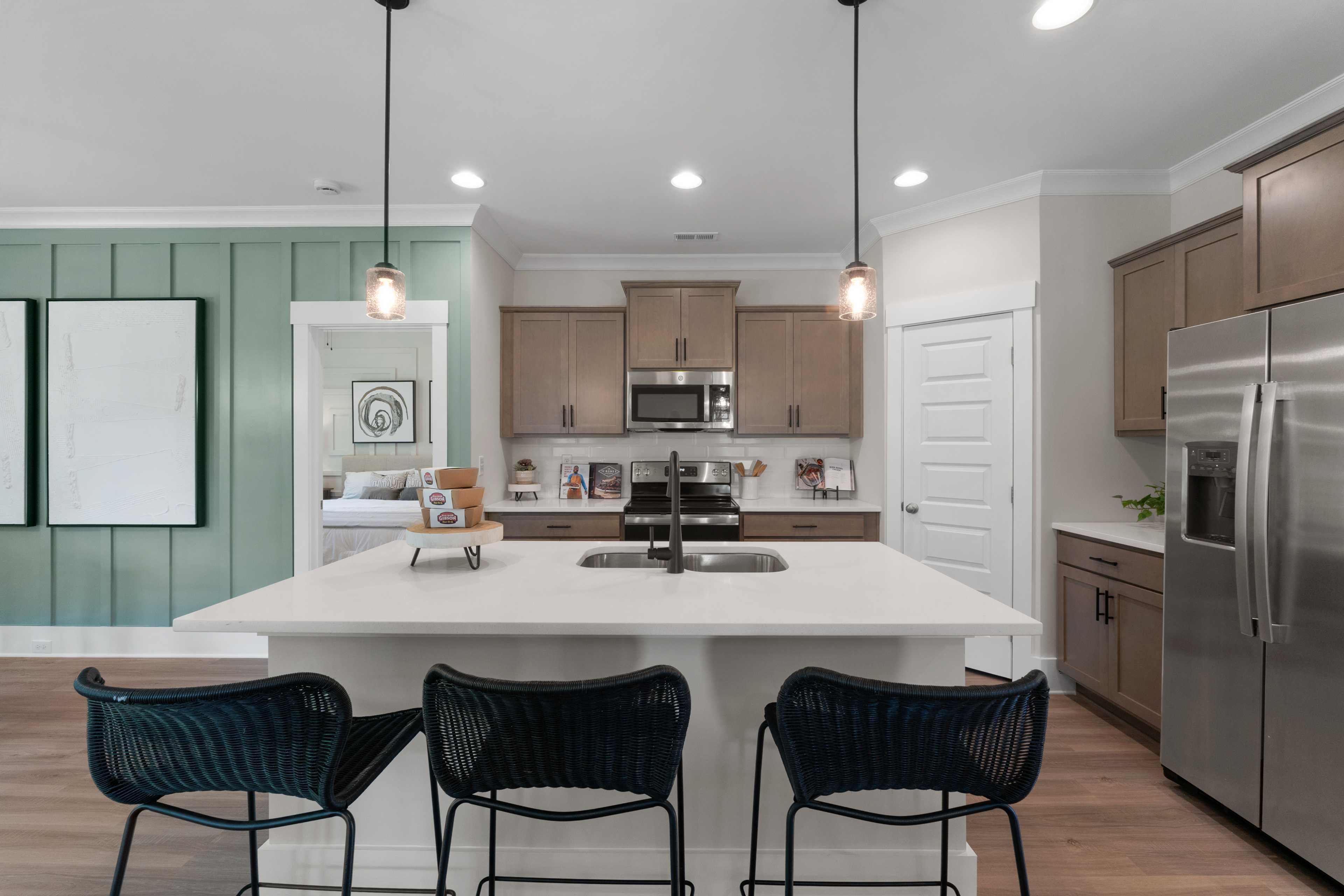 Modern kitchen with quartz island, blue bar stools, stainless appliances in Hollon Meadow Decatur AL