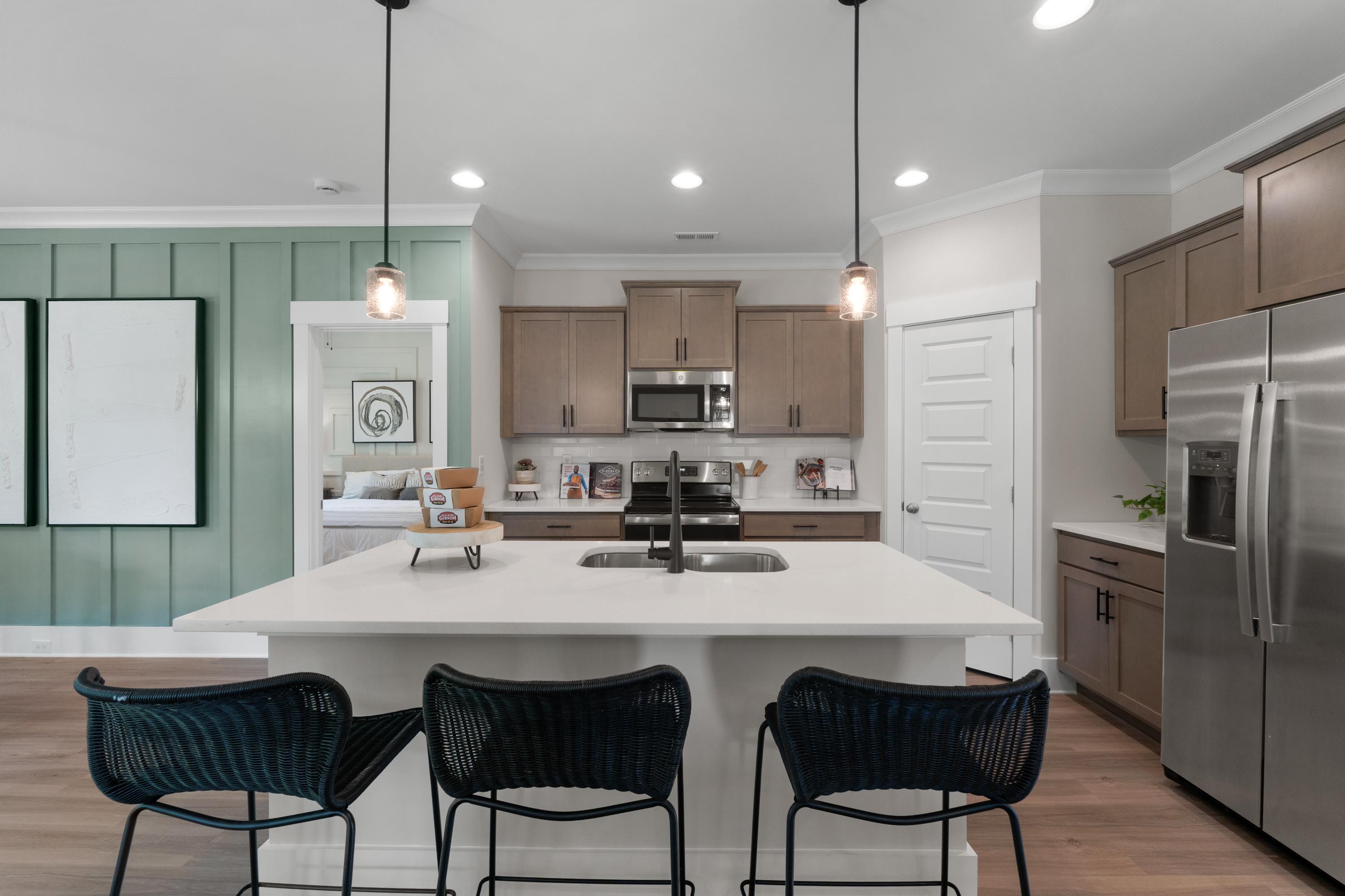 Modern kitchen with quartz island, blue bar stools, stainless appliances in Hollon Meadow Decatur AL