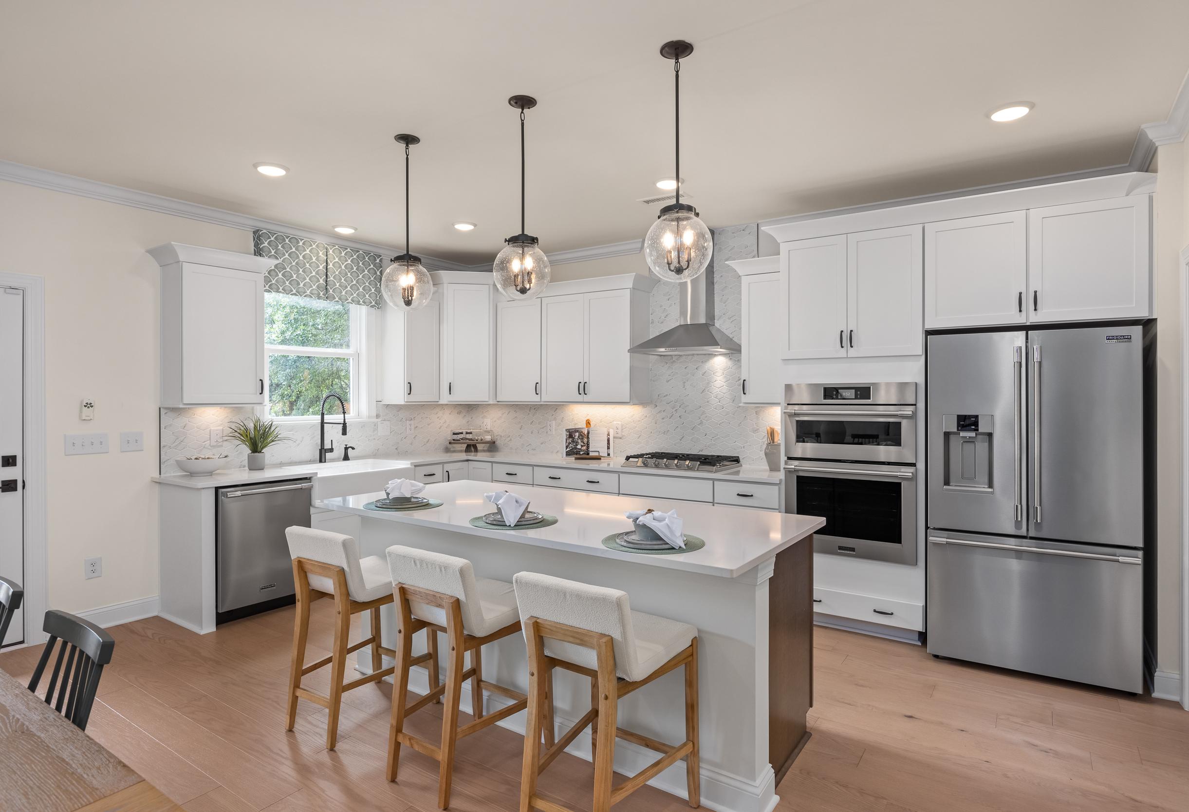 Gourmet kitchen in The Crawford by Davidson Homes: white shaker cabinets, large quartz island with bar stools, stainless steel appliances, pendant lights