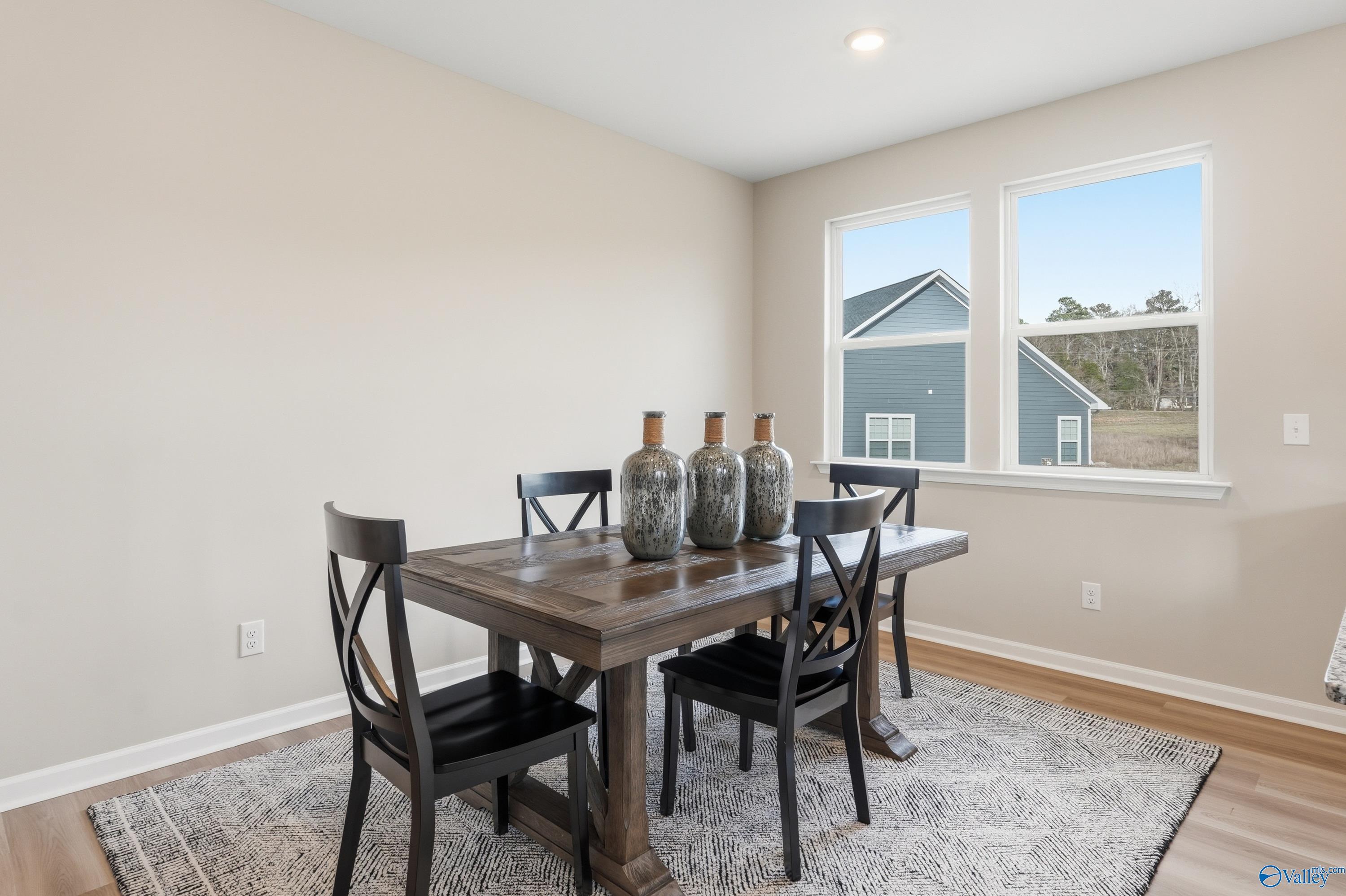 Elegant dining room with wooden farmhouse table, black chairs, and tall vases, large windows in The Polaris home, Fayetteville, TN