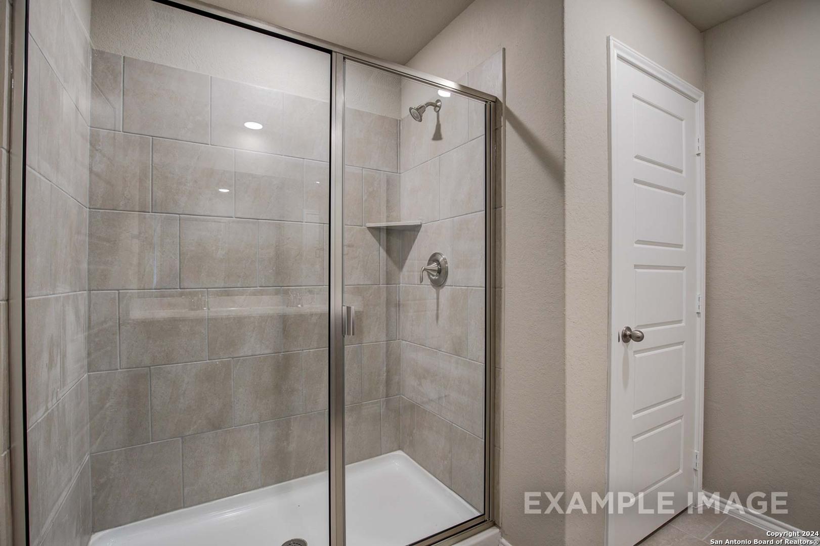 Frameless glass walk-in shower with gray subway tiles and built-in shelf in master bath of Davidson Homes The Murray J, Bricewood, San Antonio