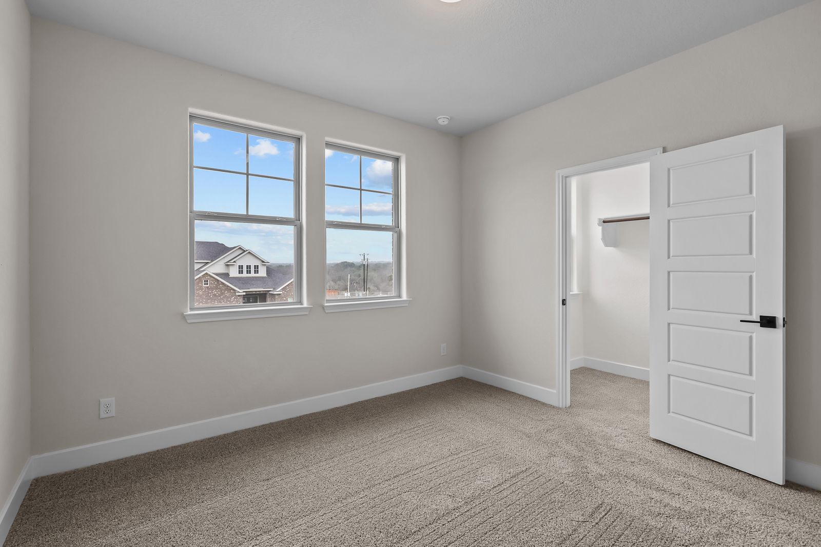 Spacious secondary bedroom in The Belmont home design featuring neutral carpet, large windows, and a walk-in closet.
